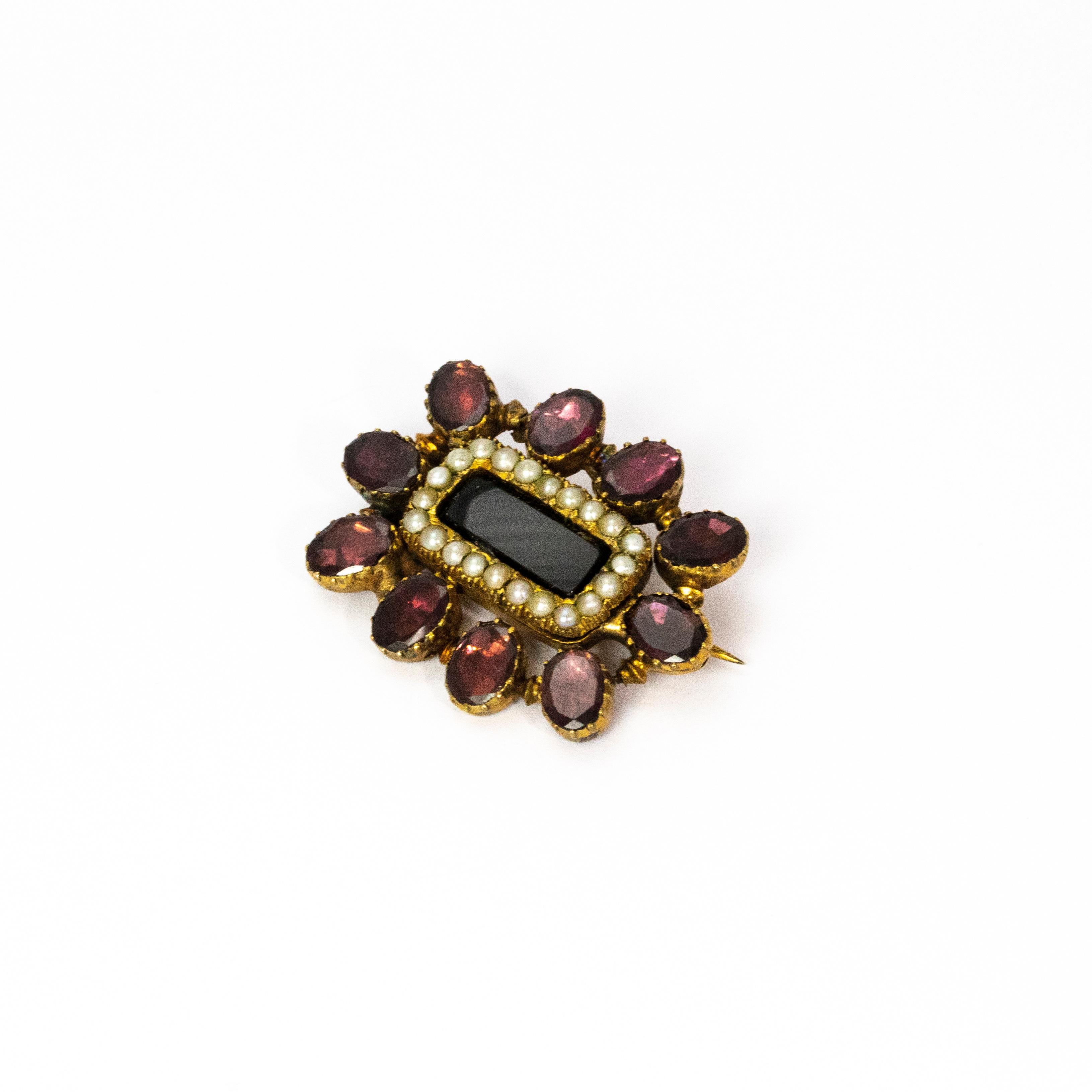 A beautiful memorial brooch from the Georgian era . The outer edge is lined with ten stunning red flat cut garnets, with an inner circuit of split seed pearls. Modelled in 9 karat yellow gold