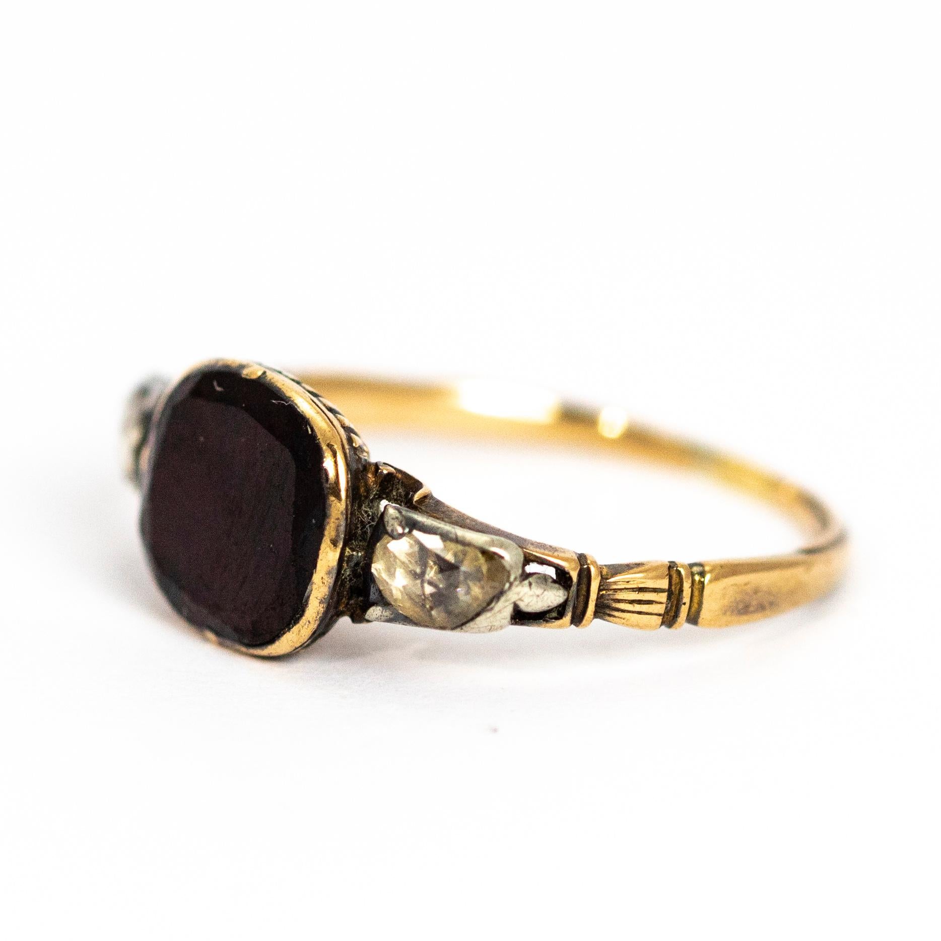 This wonderful Georgian ring holds a large flat cut garnet which sits between two single, good sized rose cut diamonds. The underneath of the garnet setting has lovely detail of its own. This ring is in lovely condition and is modelled out of 18