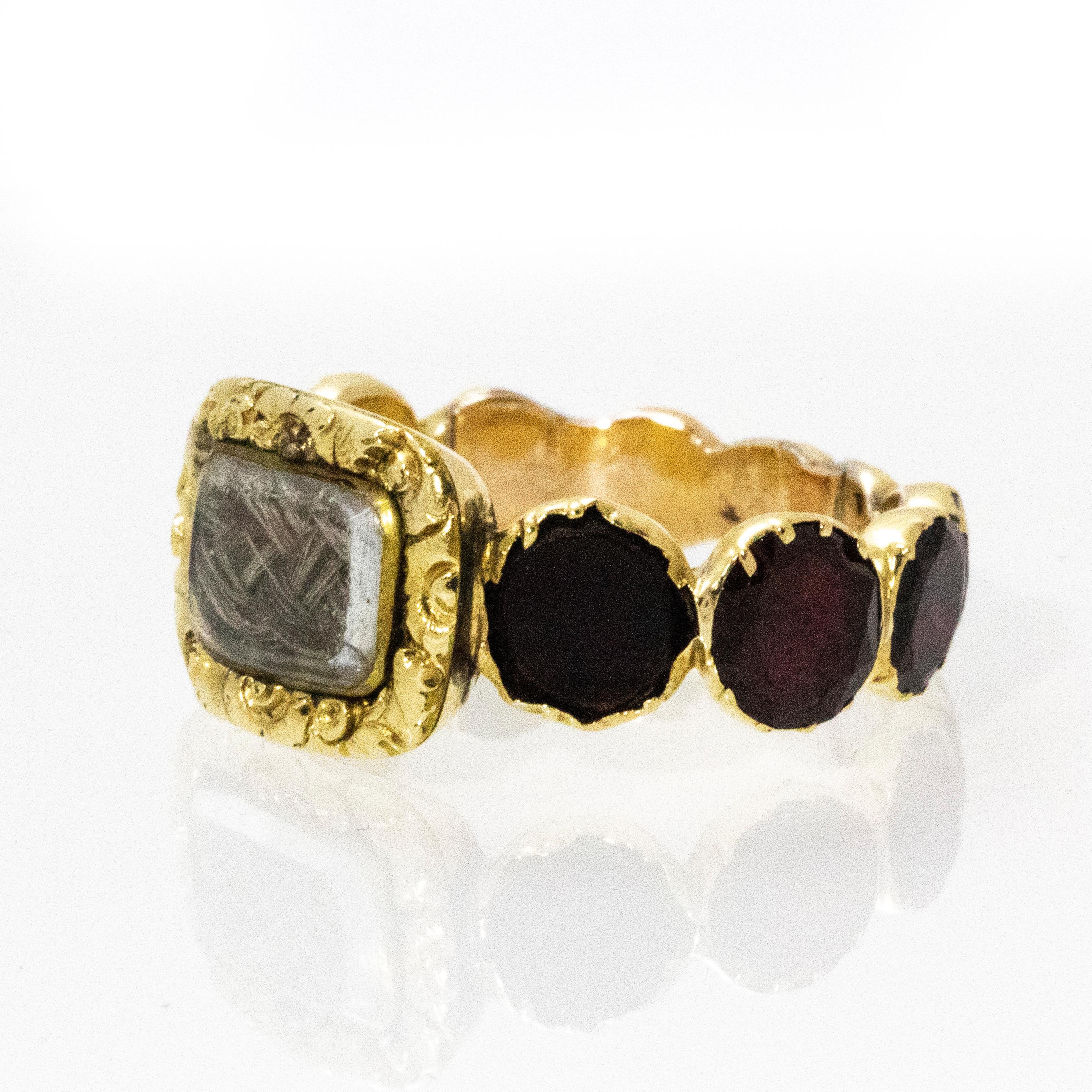 Lovely example of mourning jewellery. This ring boasts ten beautiful flat cut garnets all hugged by gold. The main attraction has to be the delicately plaited hair held in a glass fronted panel surrounded by a decorative 15ct gold frame.

Ring Size: