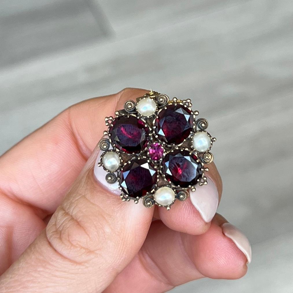 This stunning brooch would also make a stunning pendant! There are four large flat cut garnets and at the centre is a run garnet. The brooch is also decorated with pearls. 

Brooch Diameter: 25mm

Weight: 7.9g
