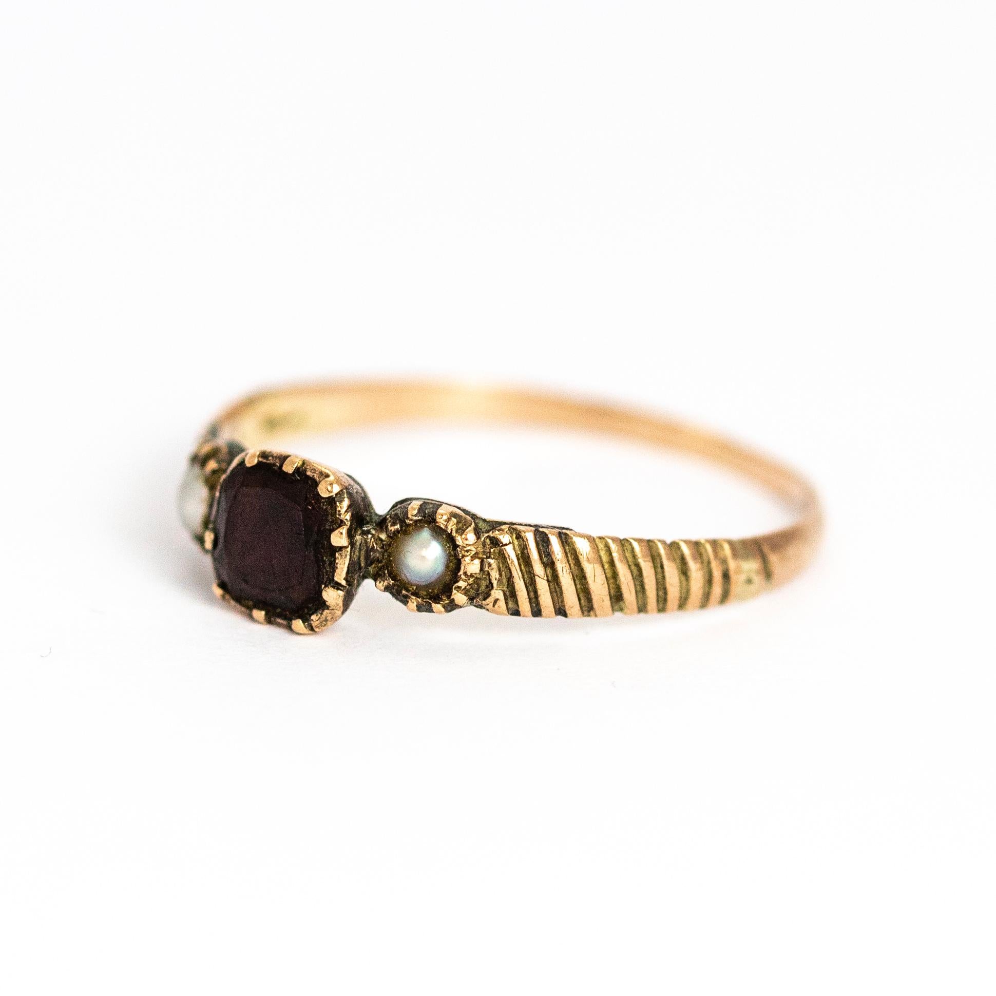 A superb antique Georgian three-stone ring. Centrally set with a beautiful flat-cut garnet flanked by fine seed pearls and hand-chased textured shoulders. Modelled in 9 karat yellow gold.

Ring Size: UK N, US 7