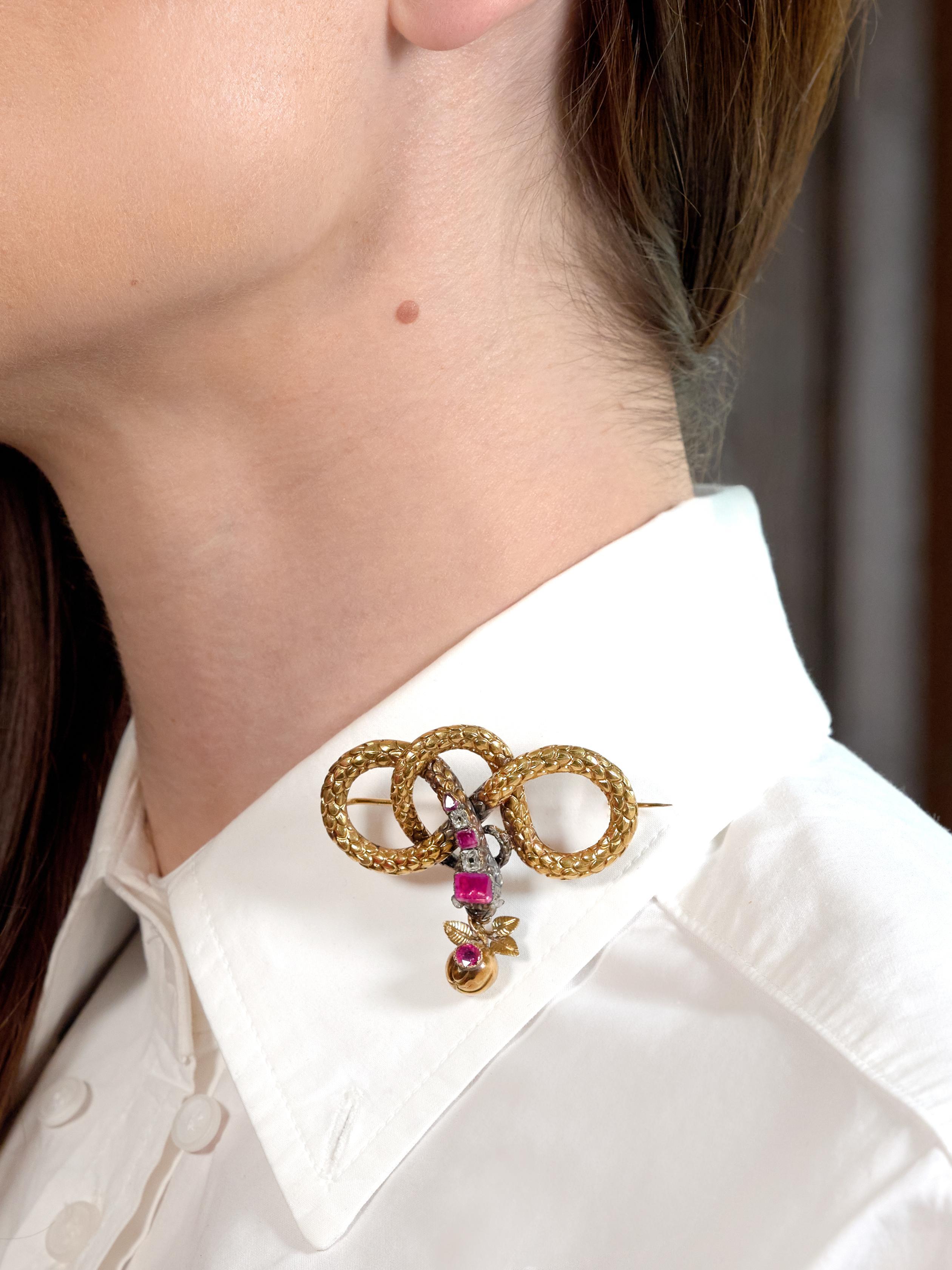 Diseñado como una estilizada serpiente anudada en remolino que suspende un amuleto de manzana de la boca
El cuerpo dorado está profundamente estriado con escamas y acentuado por la cabeza rematada en plata
Acentuado por rasgos faciales acanalados,
