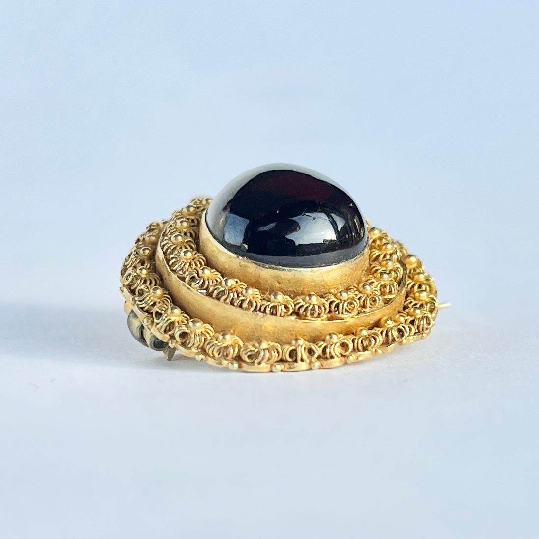 This gorgeous 18 Carat gold cannetille brooch holds a shiny red garnet stone. The detail surrounding this stone is exquisite. This piece could be either a brooch or a pendant. 

Face Diameter: 24mm

Weight: 7g