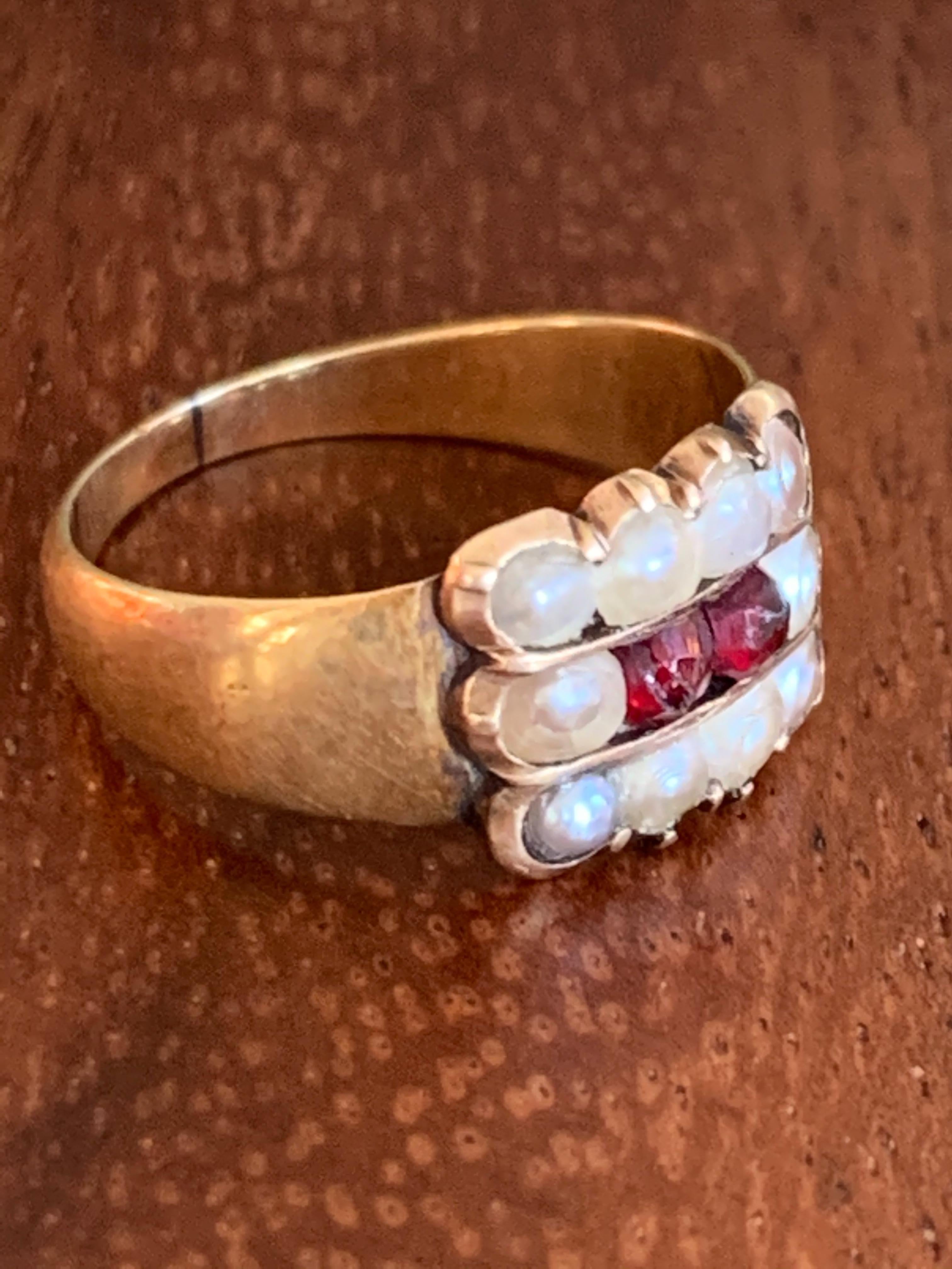 This Georgian ring is so elegant in its simplicity.  It features ten Pearls which stand guard over two faceted Garnet stones in a 14 karat yellow Gold setting. 

Size: 5 1/2 - this ring is resizable but vendor does not offer sizing services.