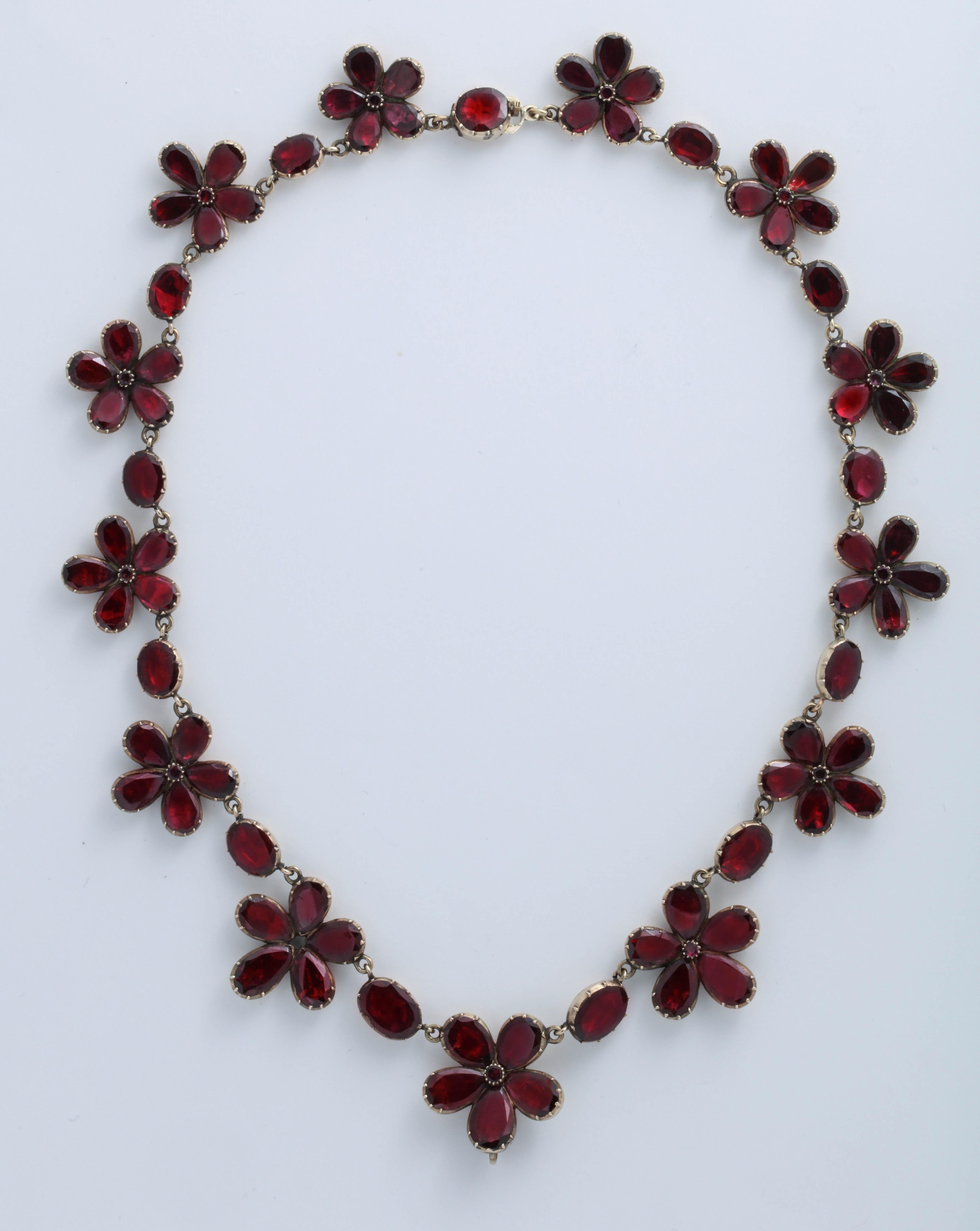 Set with beautifully matched almandine garnets, the necklace alternates between flower clusters and ovals. 15K gold. English, early 19th century. 