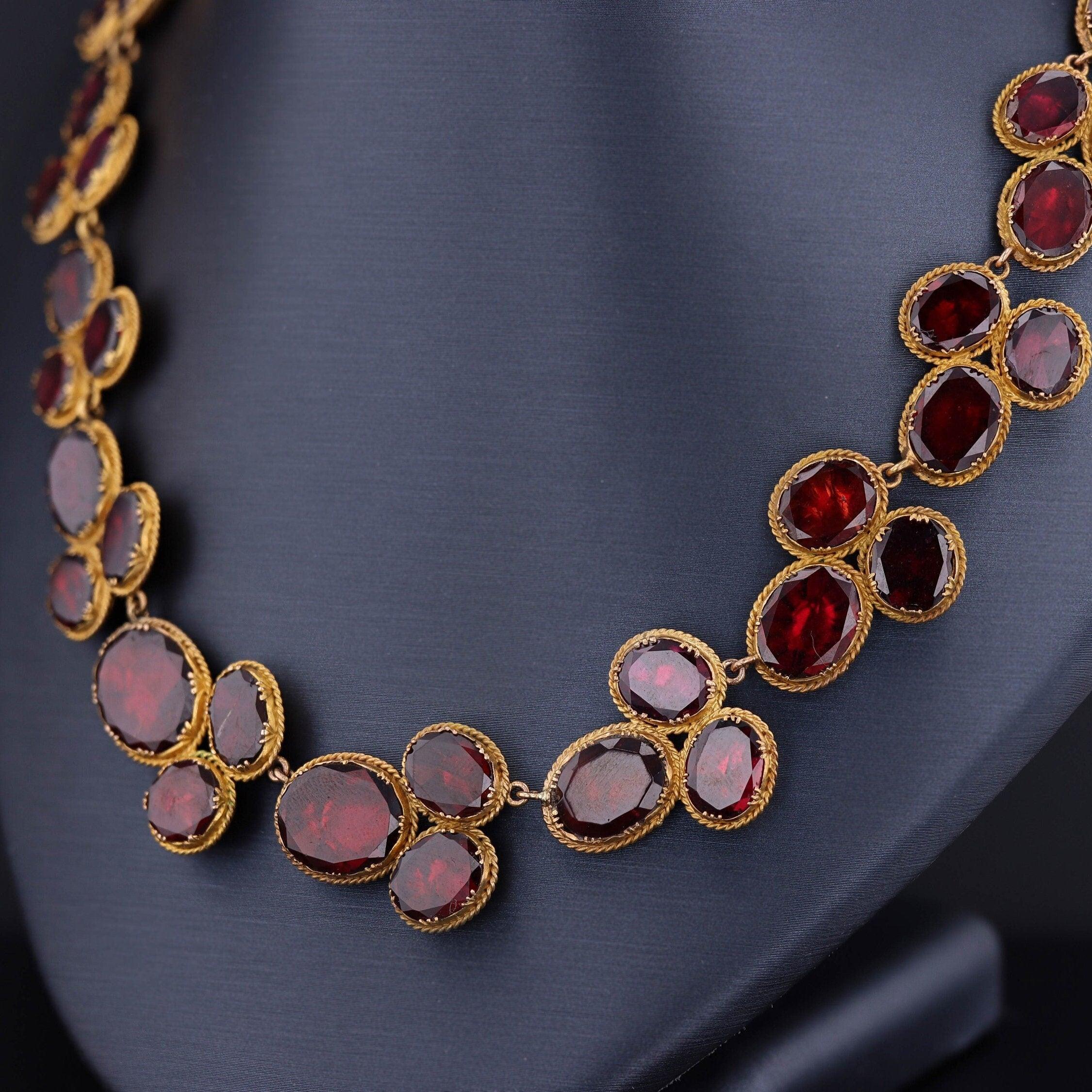 Découvrez l'élégance intemporelle de ce remarquable collier ancien datant de la fin de l'ère géorgienne (vers 1820). Réalisée avec un art méticuleux, cette pièce exquise met en valeur 54 grenats ovales à taille plate, sertis dans de l'or fleuri 14k