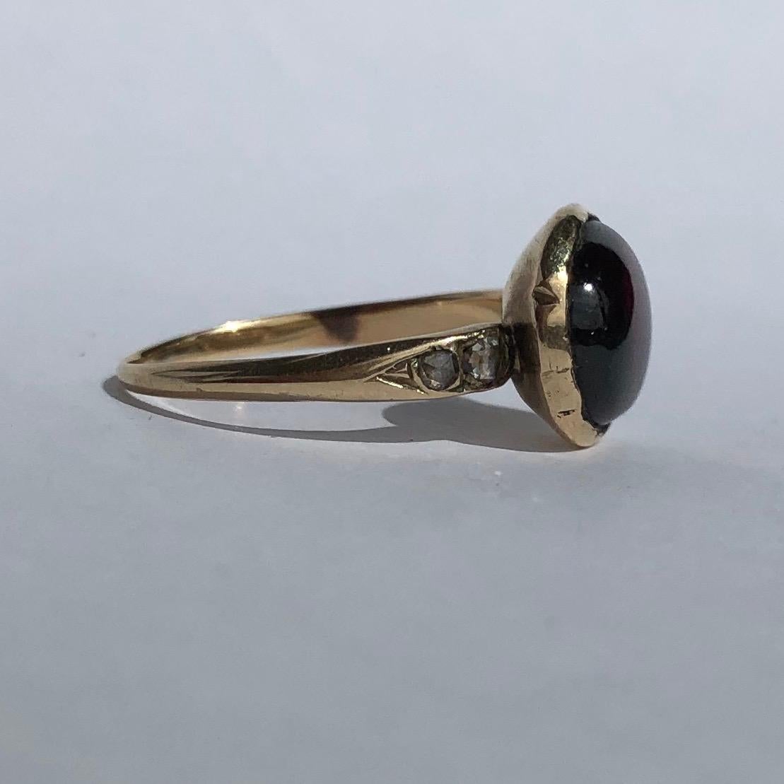 At the centre of this ring there is a deep glossy red garnet and either side of this stone sits a pair of rose cut diamonds. The settings and shoulders are typically Georgian and the shoulders have some really lovely detail to them. 

Ring Size: M