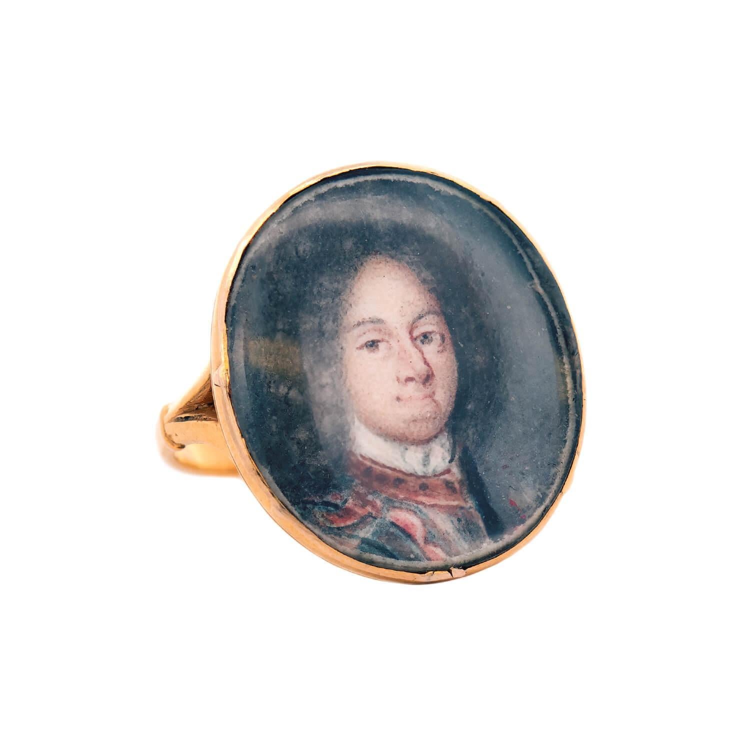 An exquisite and unusual ring from the Georgian (ca1750s) era! Crafted in 14k yellow gold, this ring features a circular centerpiece, which holds a hand-painted portrait. The portrait depicts Ludwig Wilhelm von Baden (aka Louis William), who acted