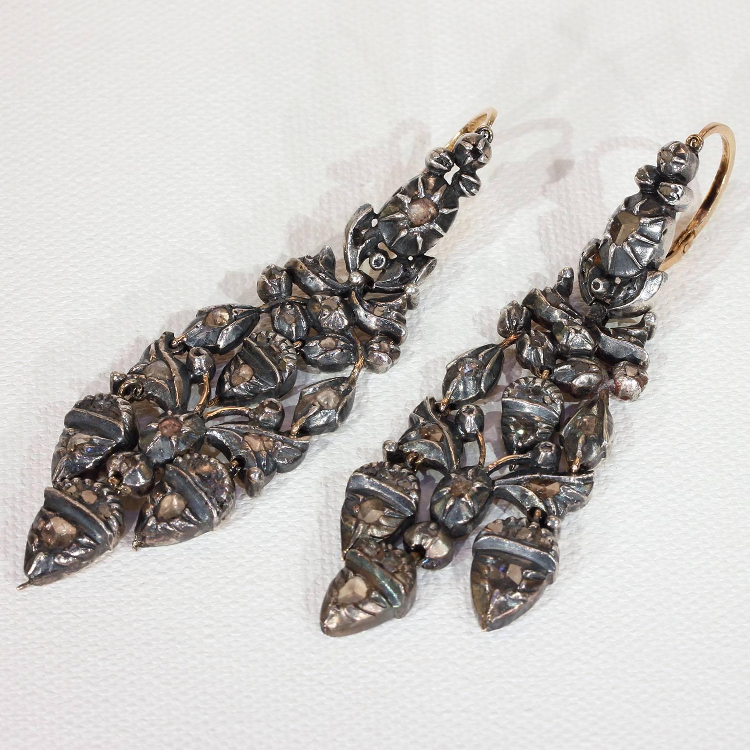 These fabulous, long statement earrings were hand crafted in the Georgian era, around 1780. They feature an acorn and oak leaf motif and are set with table cut rose diamonds. These earrings are sterling silver over 14 karat gold and are probably