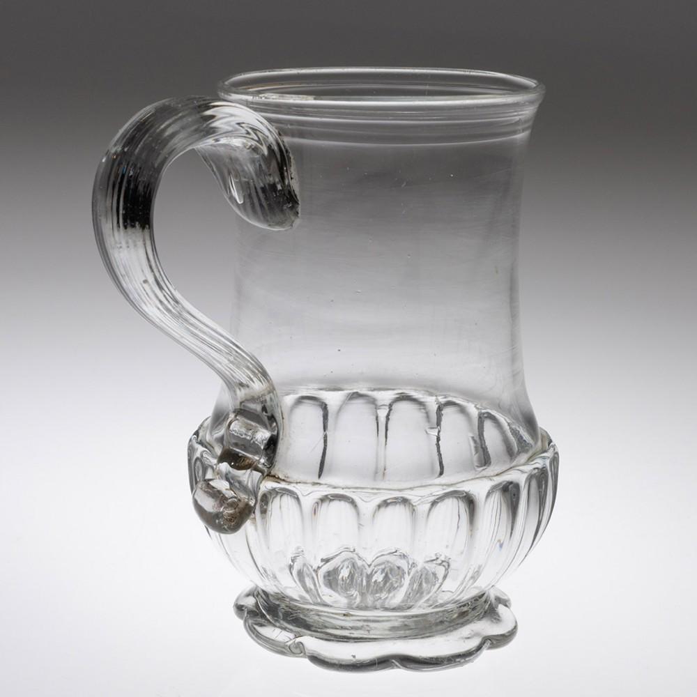 Georgian Glass Tankard, c 1780

Additional information: 
Period : George III
Origin : England 
Colour : Clear 
Bowl : Baluster-shaped with reeding under rim and gadrooned base; applied ribbed 'top down' handle - ribbon-finished at base
Stem :