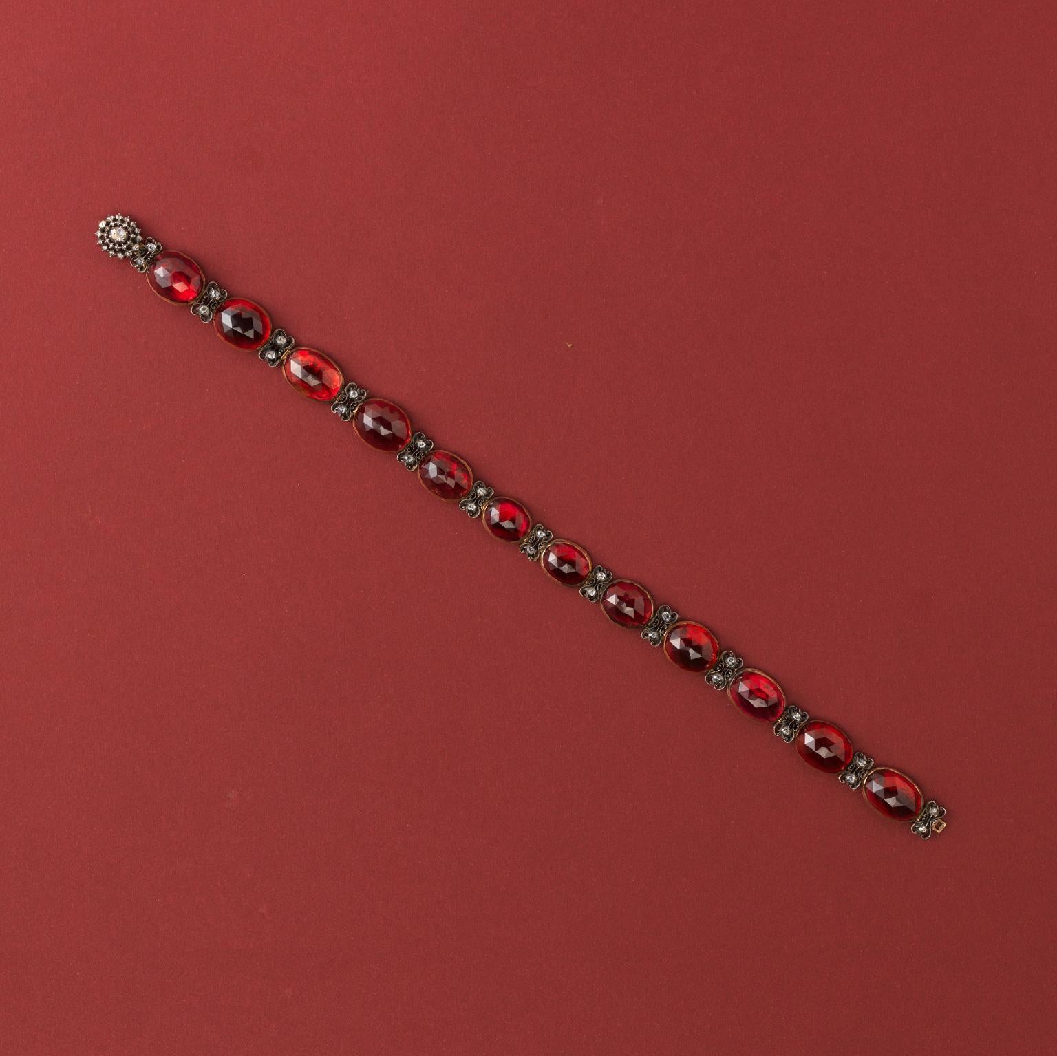 A collier de chien consisting of 12 large oval rose cut garnets set in gold alternated with floral silver elements in which are two old cut diamonds vertically set decorated with a tulip decoration also at the back, circa 1820, Dutch, to be worn