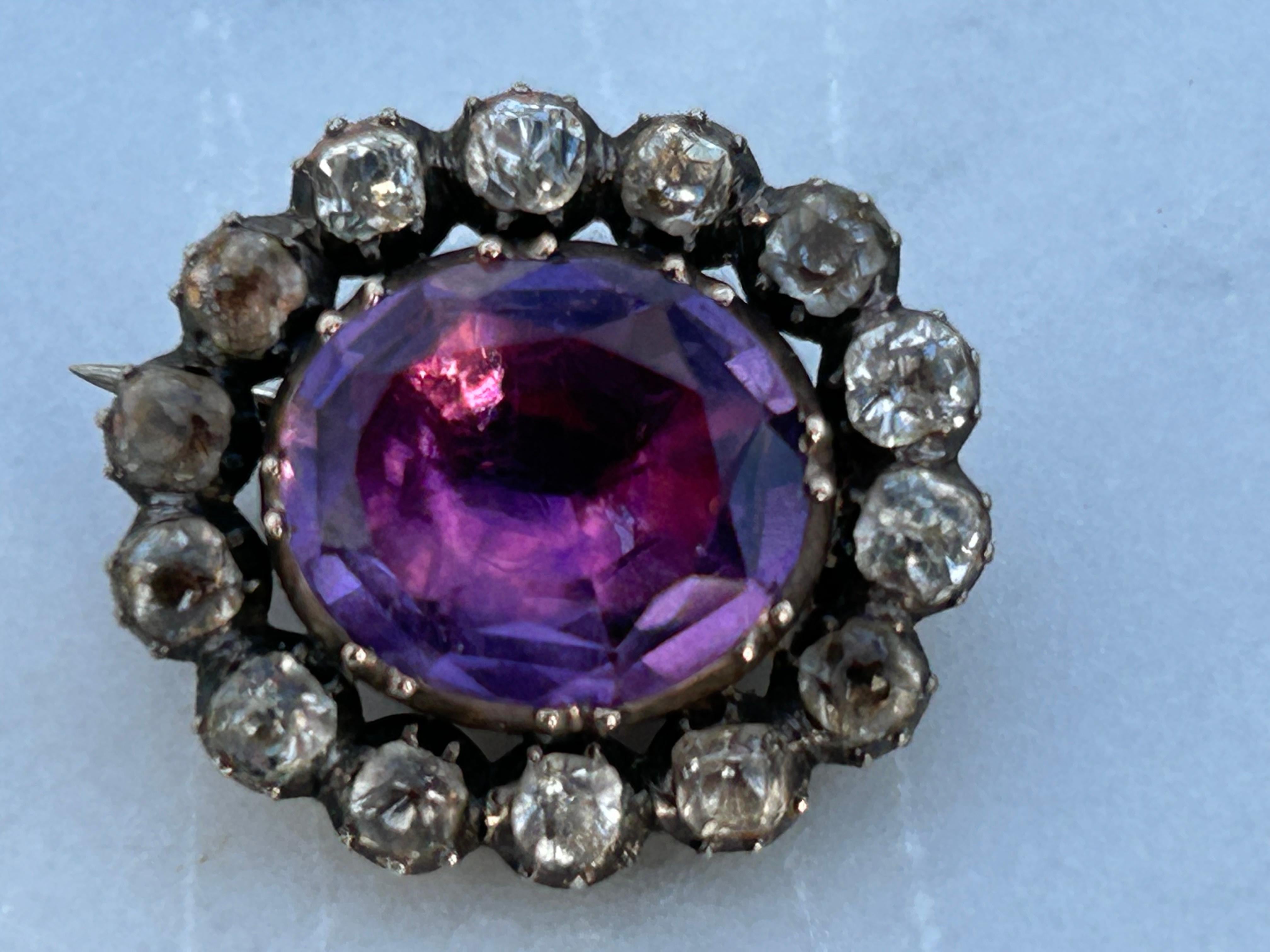 An adorable Georgian deep purple and deeplyly saturated Amethyst and Colorless Paste, Oval Brooch, gold back and silver set mounted with a foil back. Unmarked. Weight 3.1 g. Width 1.9 cm.