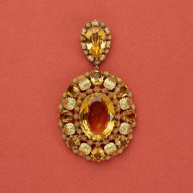 Gold pendant consisting of two parts. The upper part is set with a big pear-cut citrine with a border decorated with gold leaves and cannetille work with granulation. The lower part has one big oval cut citrine in the center around which is a double
