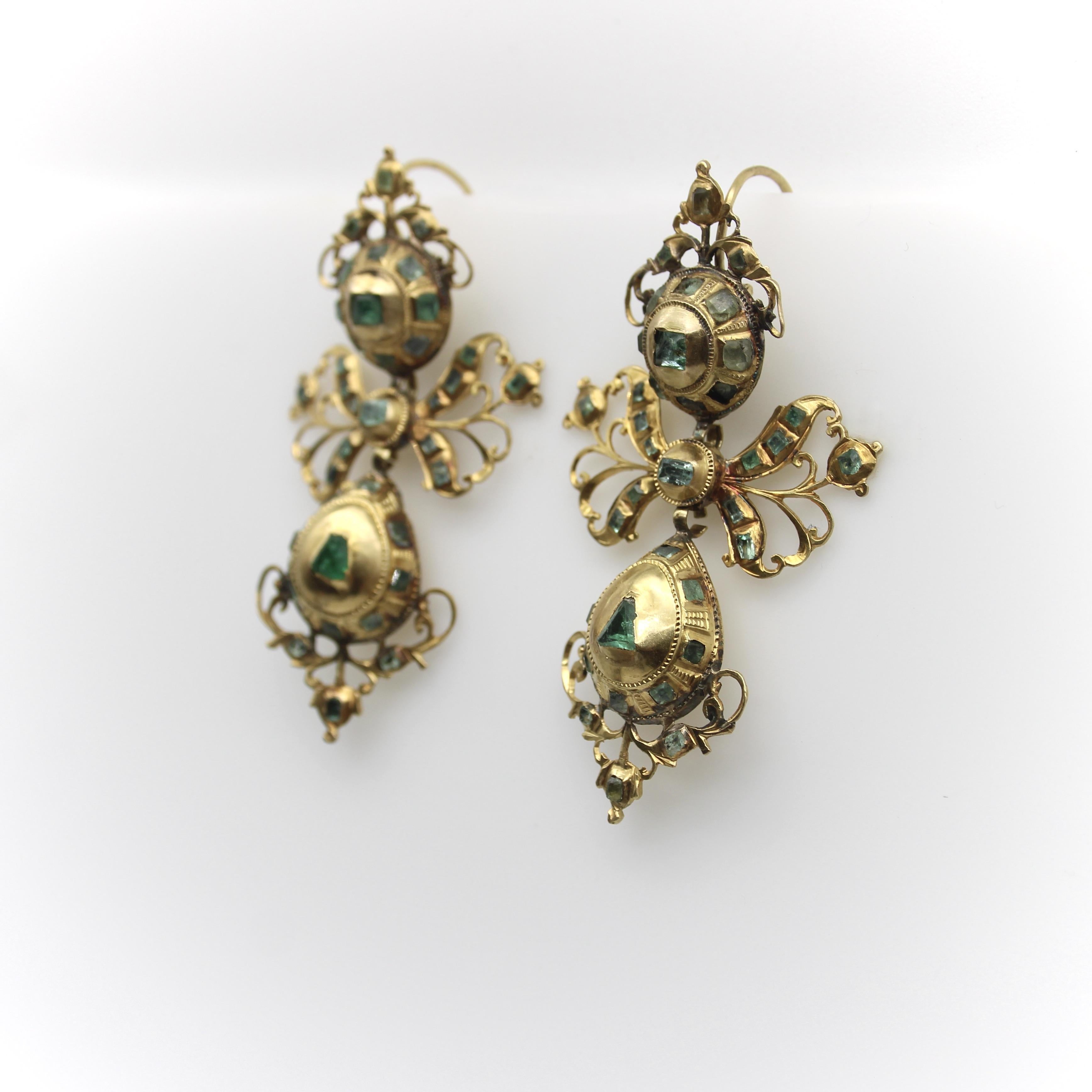 Circa 1780, these 18k gold earrings are a gorgeous example of the Iberian pendeloque design, classically seen as a cluster, bow, and drop configuration. The earrings contain 74 emeralds that make a striking contrast with the high karat gold. The top