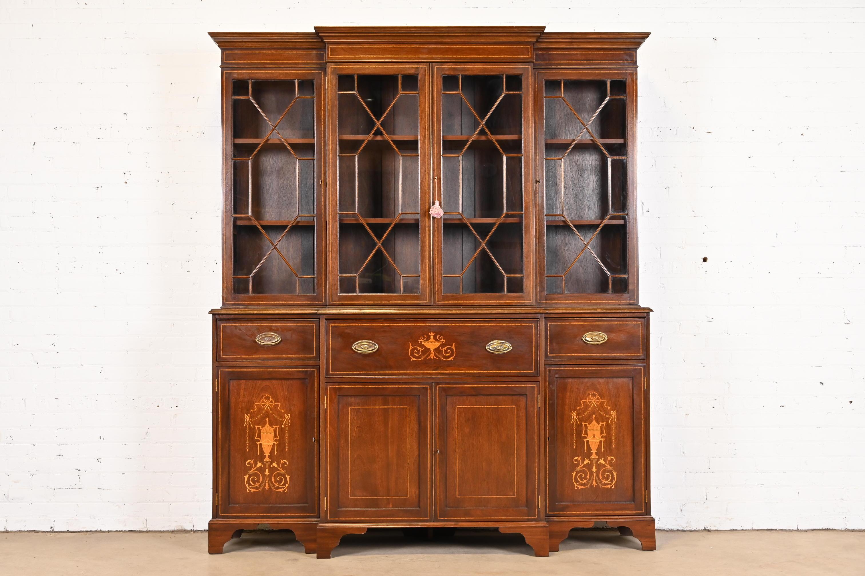 A gorgeous Georgian or Sheraton style breakfront bookcase or china cabinet with drop front secretary desk

In the manner of Baker Furniture

USA, Early 20th Century

Mahogany, inlaid satinwood marquetry, mullioned glass front doors, original