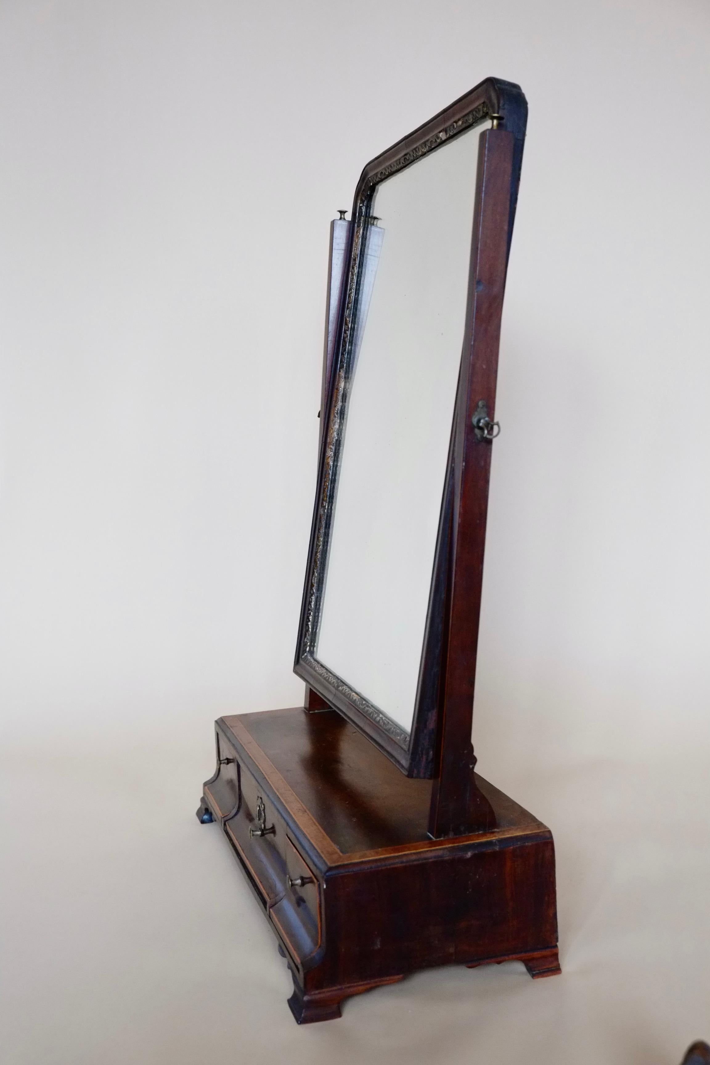 This is an antique English dressing table mirror. Georgian mahogany vanity mirror dating to circa 1800. A very handsome dressing mirror made in a rich mahogany with the most beautiful flamed burl maple inlay. The mirror plate is in very good order,