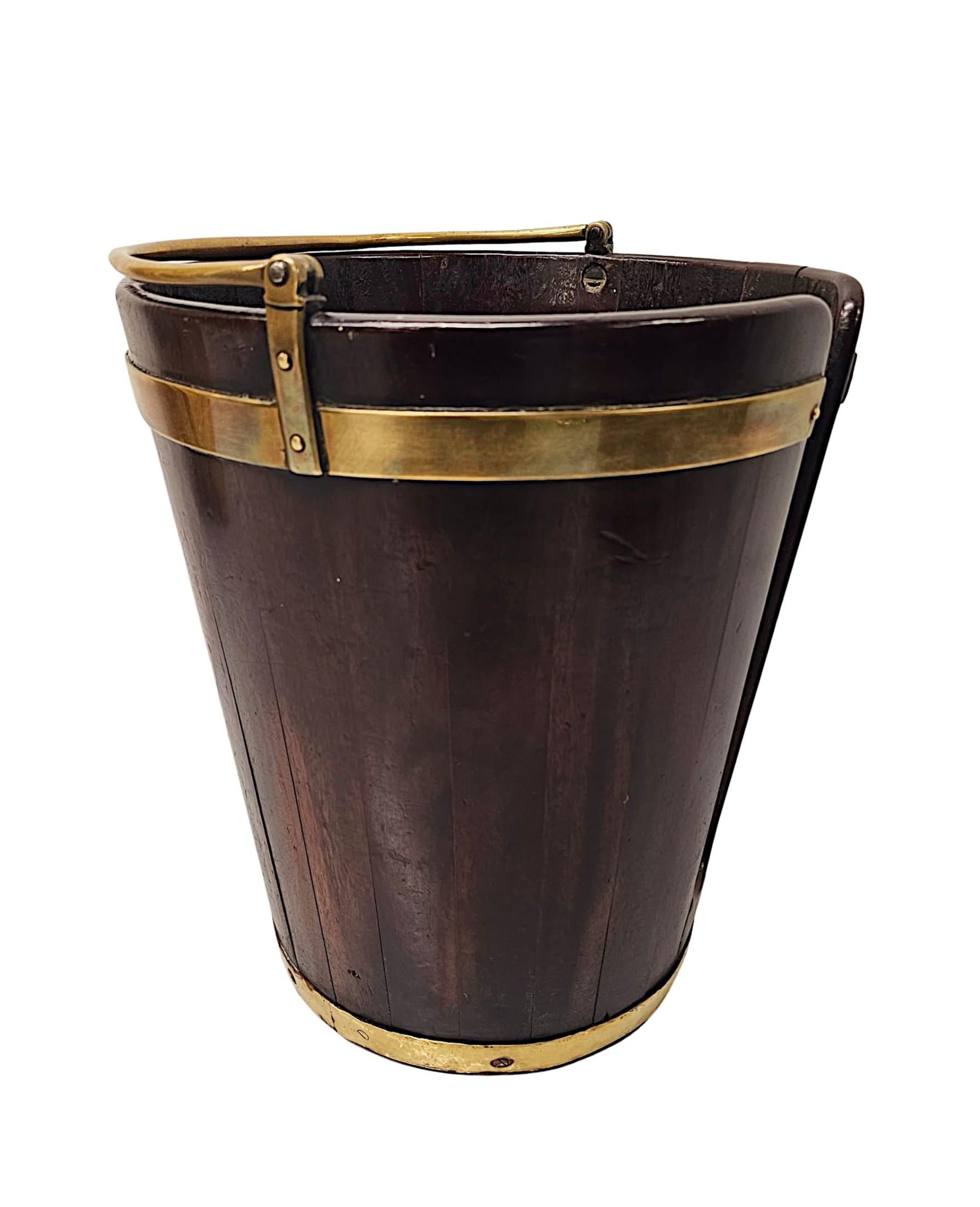 A very rare Georgian Irish brass bound well figured mahogany plate bucket, finely hand carved, of exceptional quality with beautifully rich patination and grain.  This fabulous piece is of coopered construction and features a pair of finely cast