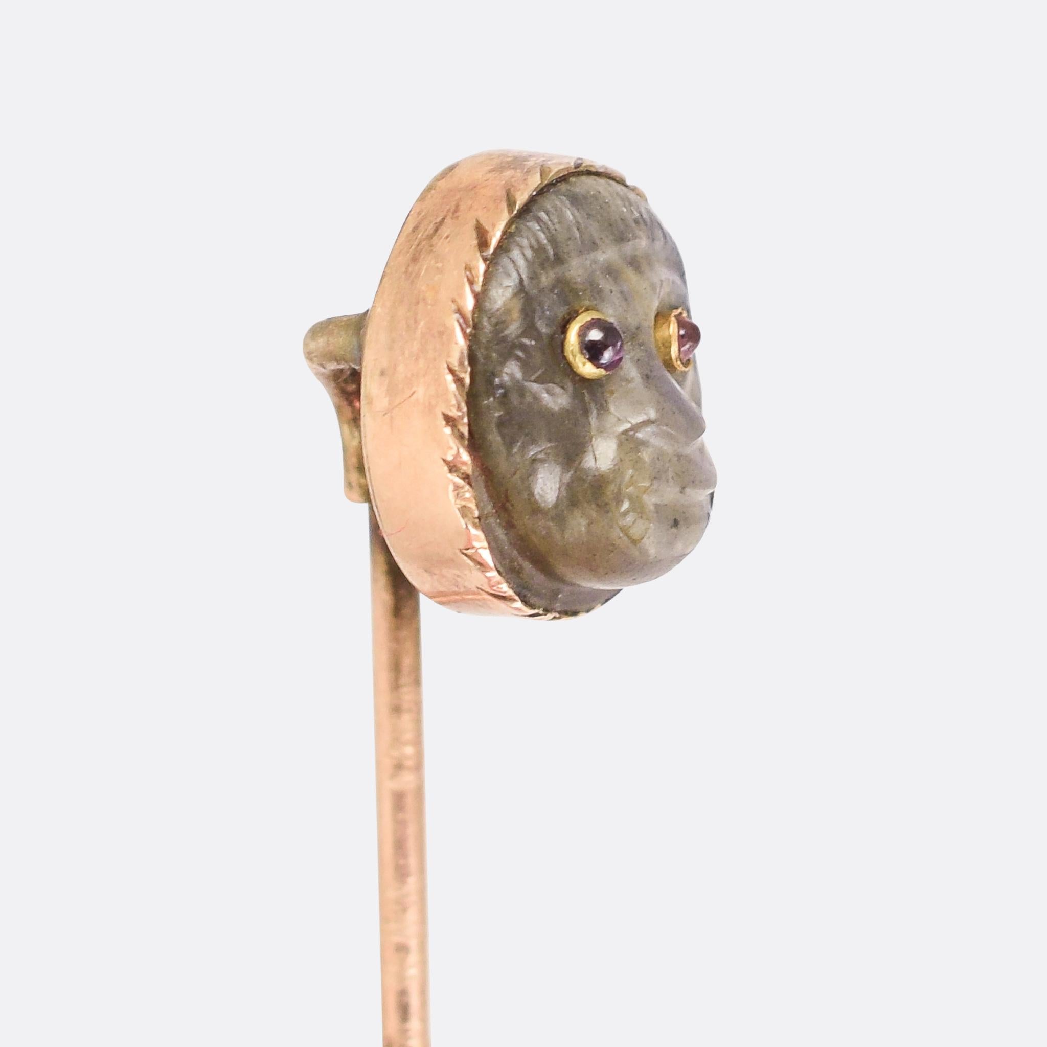 An unusual Georgian stick pin set with a carved labradorite monkey head, set with ruby cabochon eyes. The stone shimmers beautifully, with various shades of blue that form a striking contrast with the red eyes. It dates from the late 18th Century,