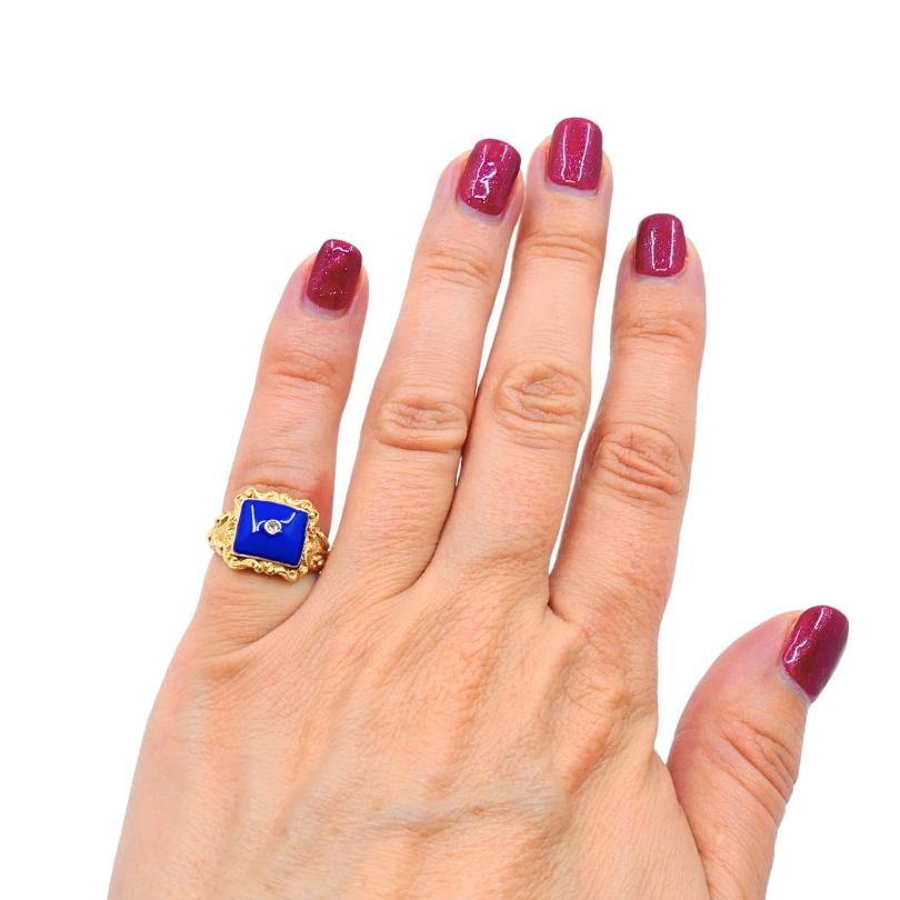 A striking Georgian ring made of 18k gold, featuring lapis lazuli and diamond. This lapis lazuli ring is square shape, with the band featuring intricate carved detailing. The ornate shank is decorated with swirling foliate motifs and textured
