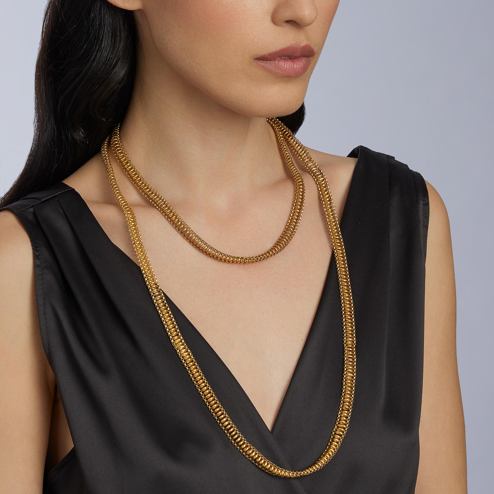 Made around the end of the Georgian period in 1830, this long chain necklace is formed of 18K gold. Of endless form, it is composed of oval polished links edged by ribbed trace link chain. Voluminous, yet soft and light, with a subtle contrast of