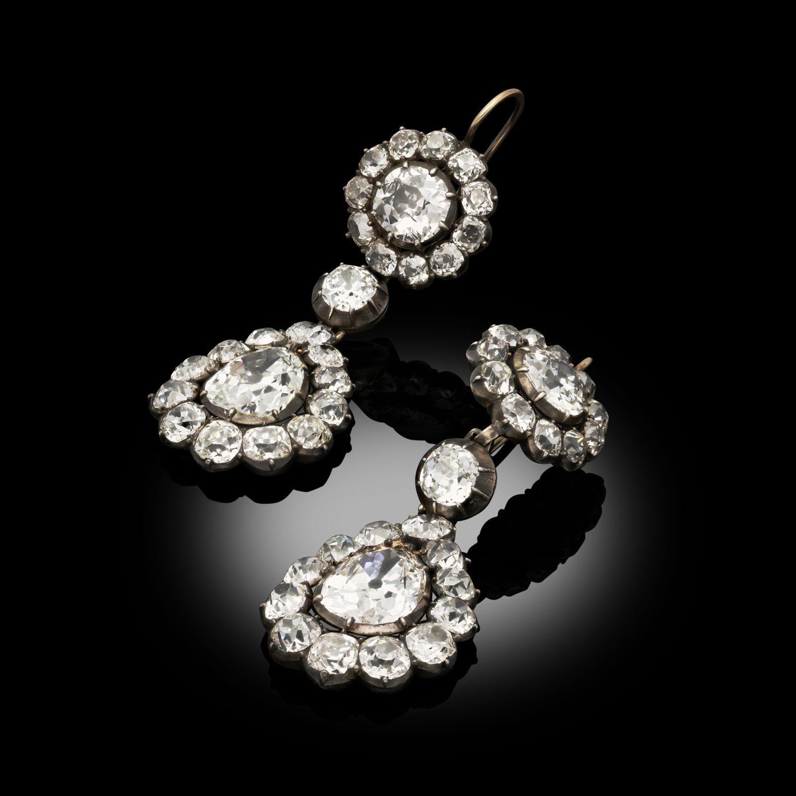 A magnificent pair of Georgian diamond drop earrings c.1800, each earring set to the top with an old European brilliant cut diamond in a cut down collet setting surrounded by a frame of smaller old cut brilliants, beneath which is a single diamond