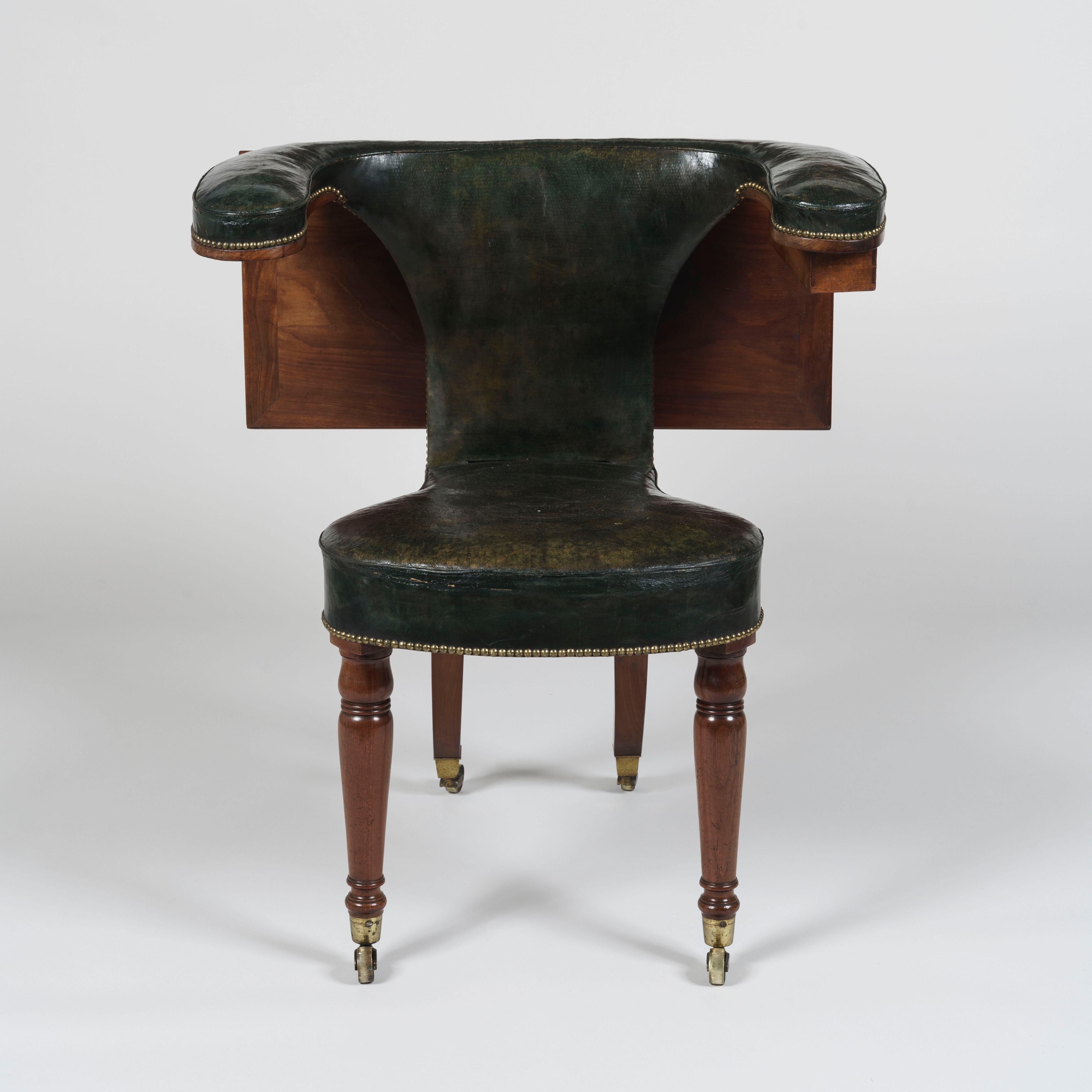 A mahogany reading chair
After a design by Thomas Sheraton

Of most striking design, the mahogany chair with its original leather upholstery having castor-shod tapering and turned front legs with sabre legs to the rear, the bowfront seat