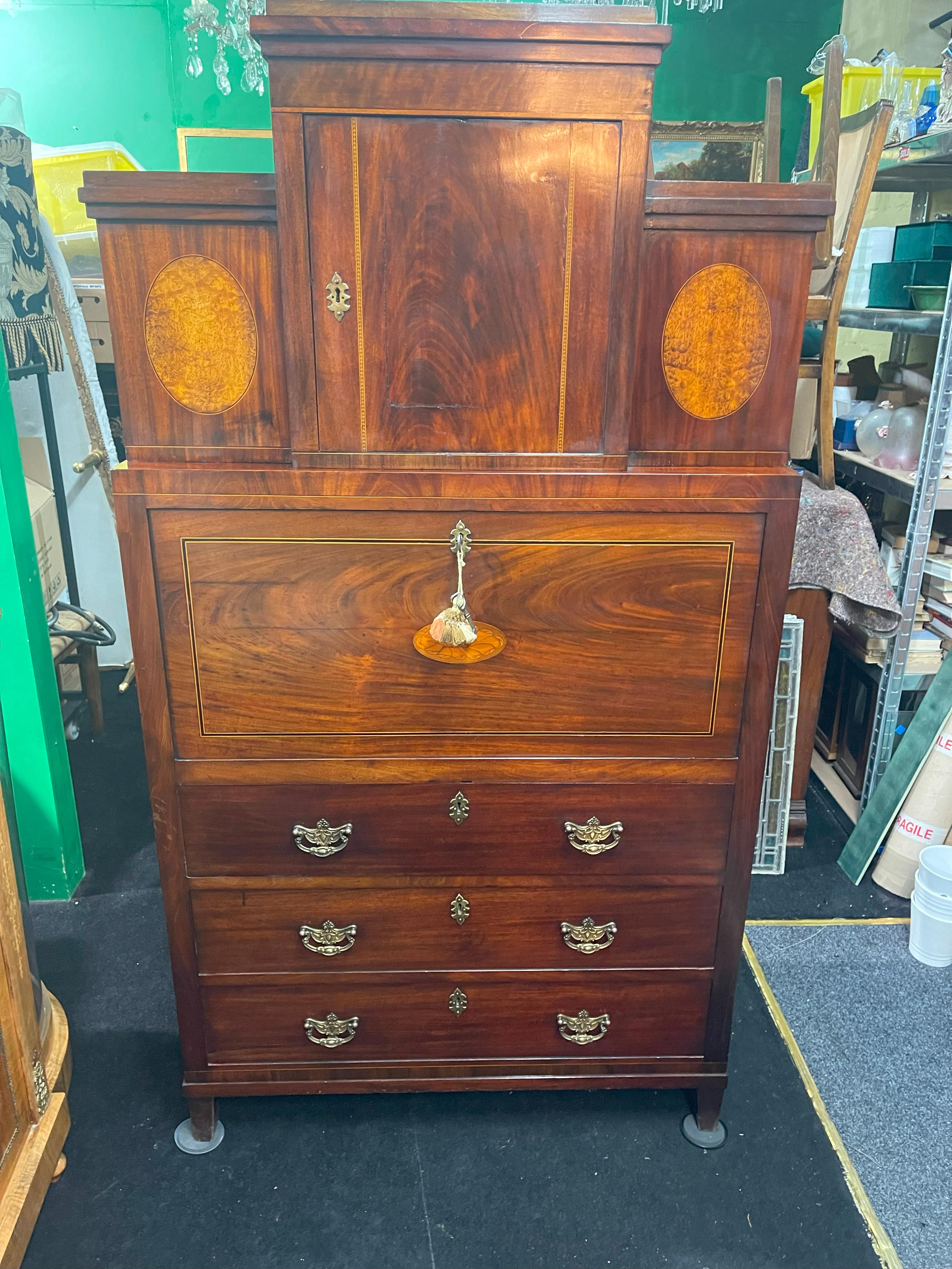 An elegant late Georgian mahogany secretaire chest of architectural form, crafted in England circa 1800.

The two-part cabinet is constructed in richly figured mahogany with satinwood and ebony stringing, and features a stepped upper section with a