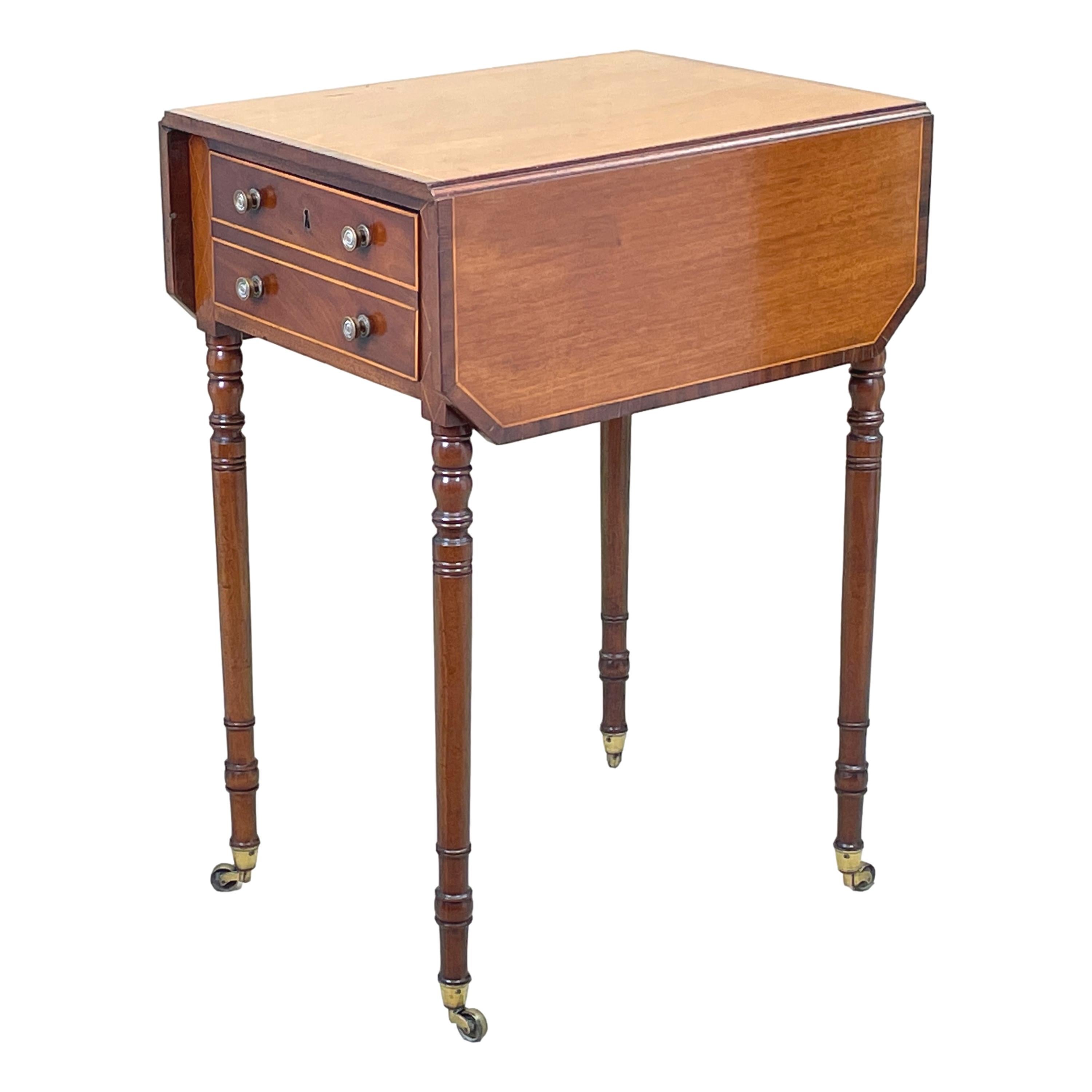 An early 19th century Georgian mahogany baby pembroke table
having shaped and crossbanded two flap top above frieze drawers
to front and reverse with inlaid decoration raised on elegant
turned legs

(Pembroke tables became one of the most popular