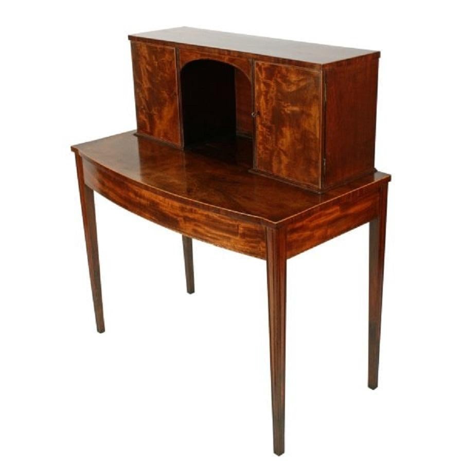A late 18th to early 19th century Georgian mahogany bow fronted bonheur du jour.

The bonheur du jour (lady's writing desk) has a pair of cupboard doors, each holding four drawers and pigeon holes and stands on four square tapering and fluted