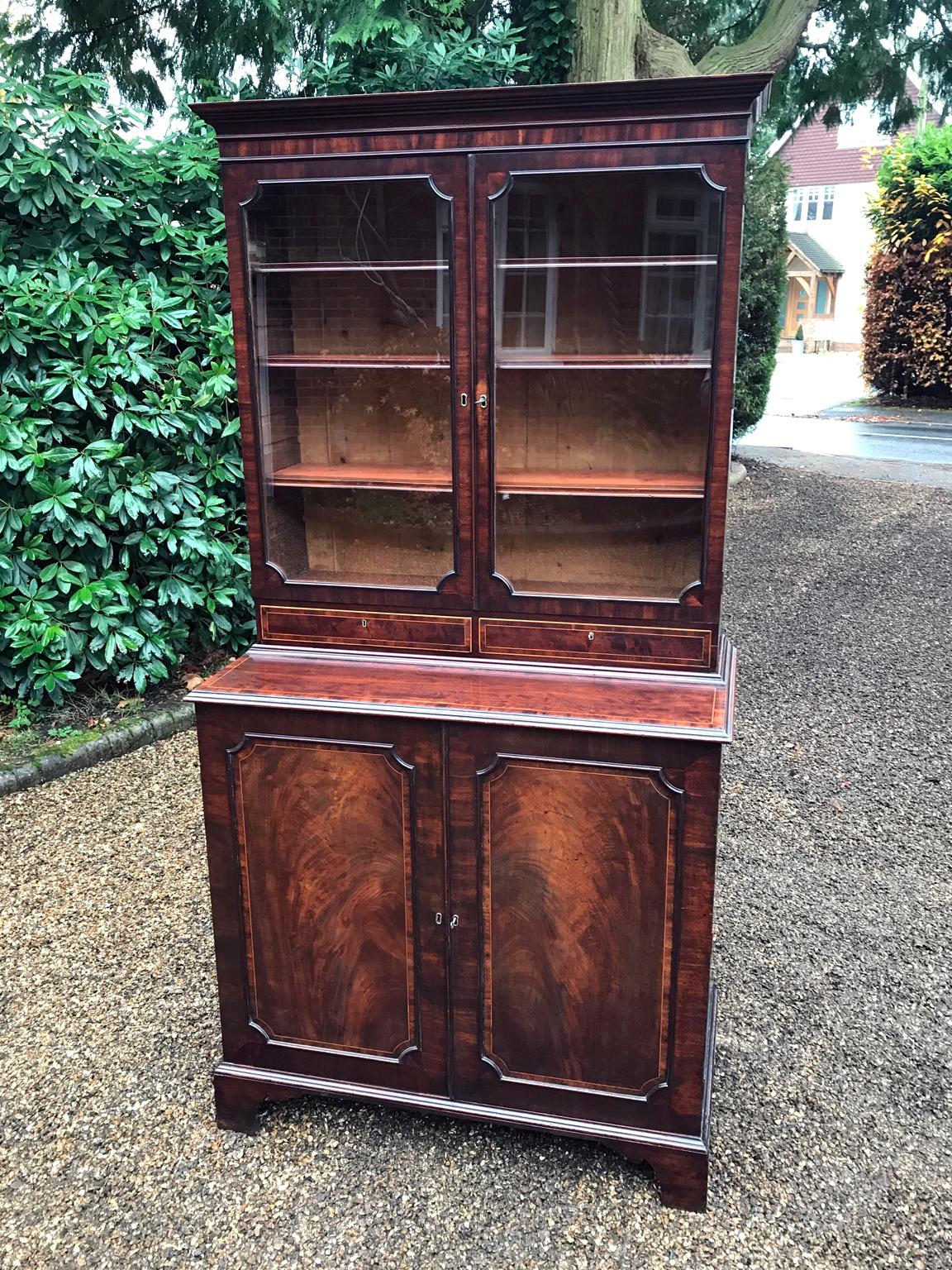A high quality Georgian mahogany bookcase and cupboard with adjustable shelves to the glazed section and two drawers below. Complete with the original 8 sliding trays in the cupboard below on bracket feet. Comes apart in two separate sections,
circa