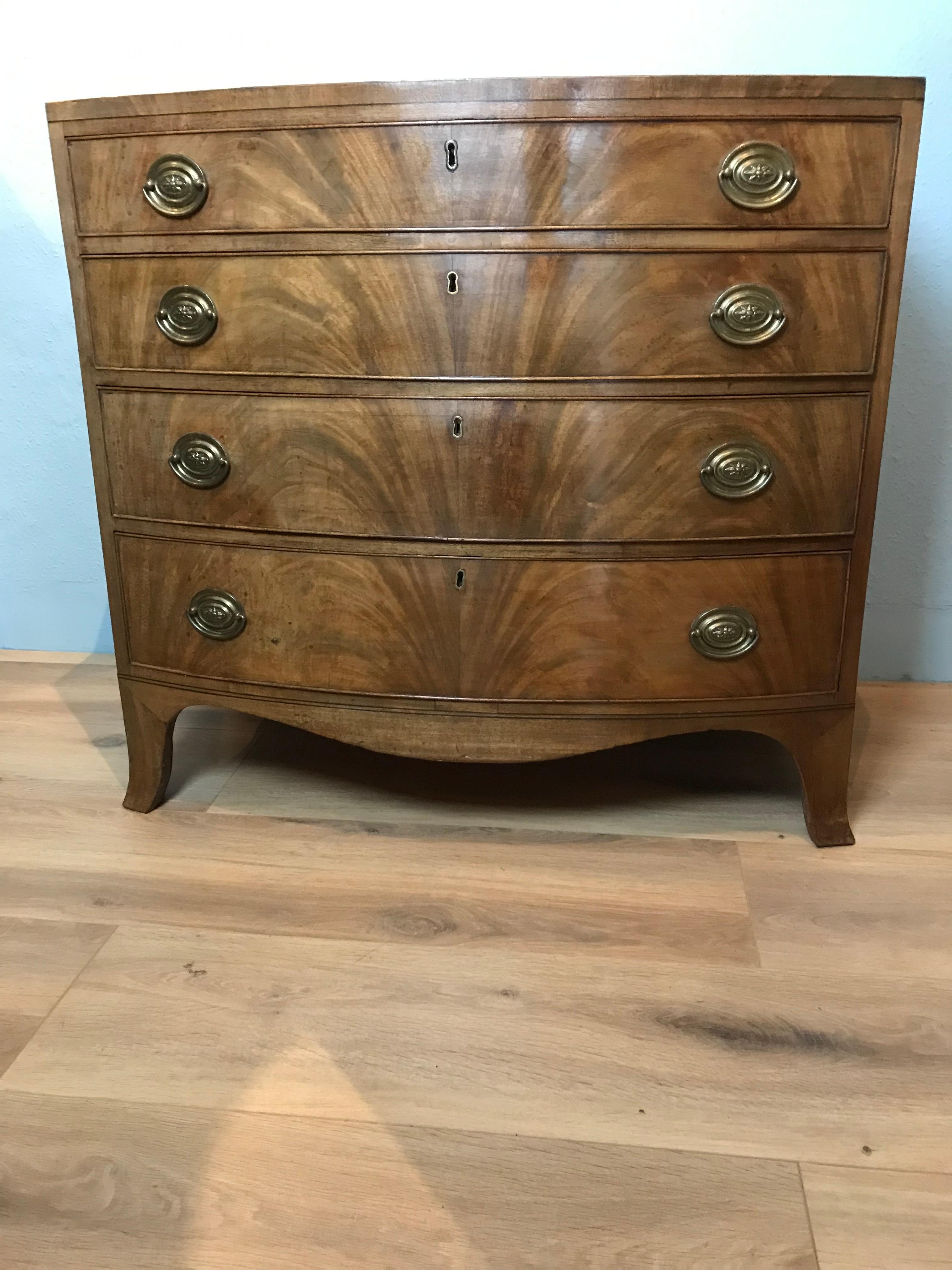 This Georgian mahogany English bow front chest of drawers has a wonderful light honey colour with book matched flame veneers to the drawer fronts. The top has an attractive cross-banding and cockbeading around each drawer. This low waisted chest of