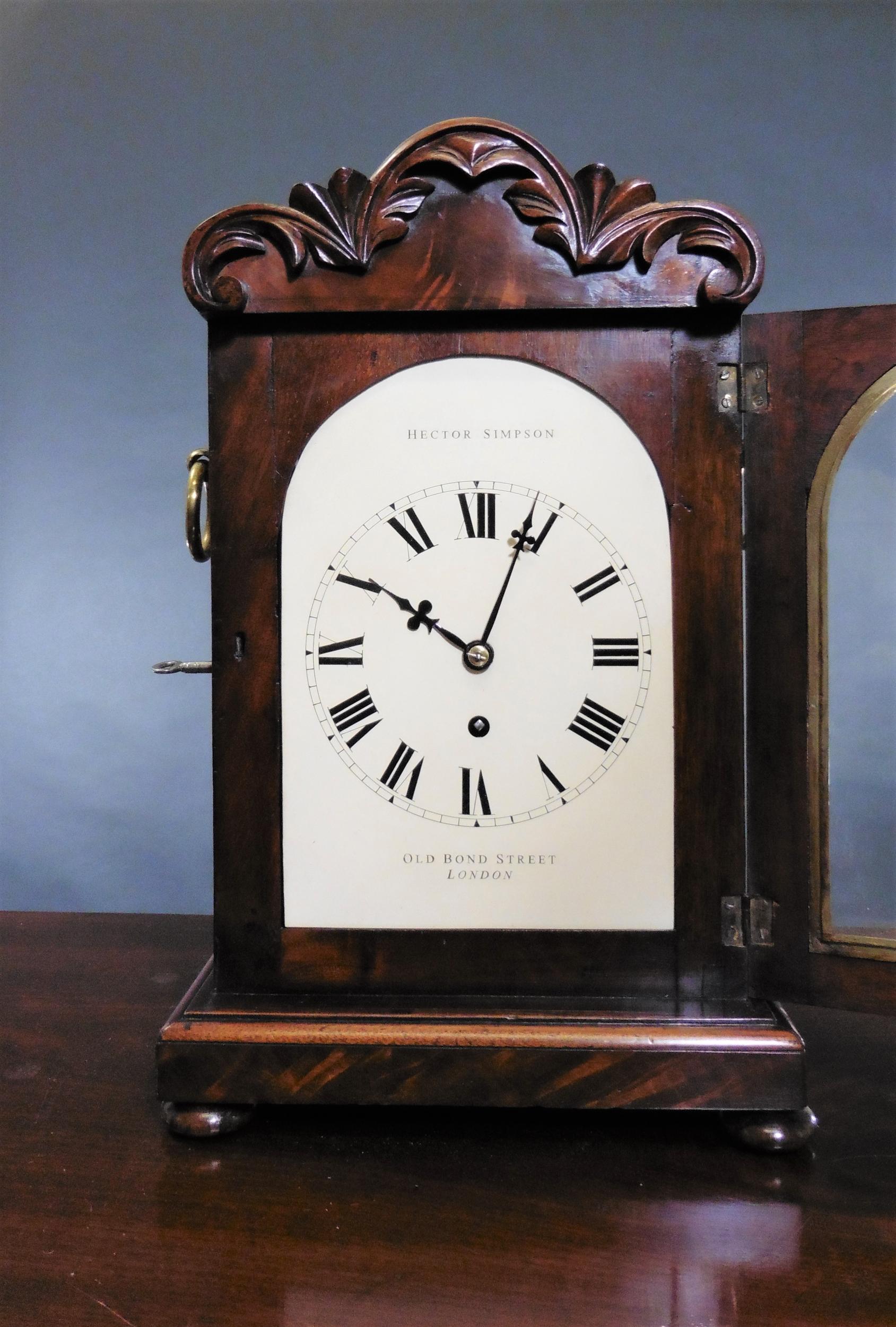 Georgian mahogany bracket clock by Hector Simpson, London.



Georgian bracket clock in a finely figured flame mahogany case standing on a raised moulded plinth and resting on four turned bun feet.

The case surmounted by a carved pediment