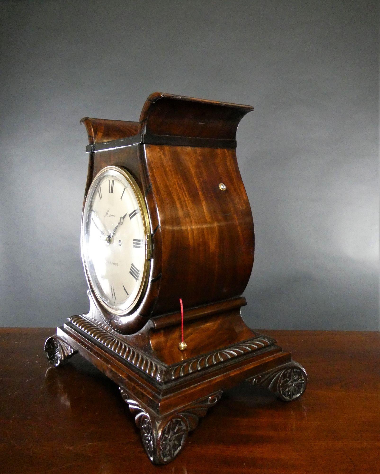 Georgian Lyre Shape Mahogany Bracket Clock by Moncas, Liverpool
Georgian mahogany English bracket clock housed in a lyre shape case with ebony inlay, resting on a beautifully carved raised, stepped plinth with carved outswept feet.  The back door