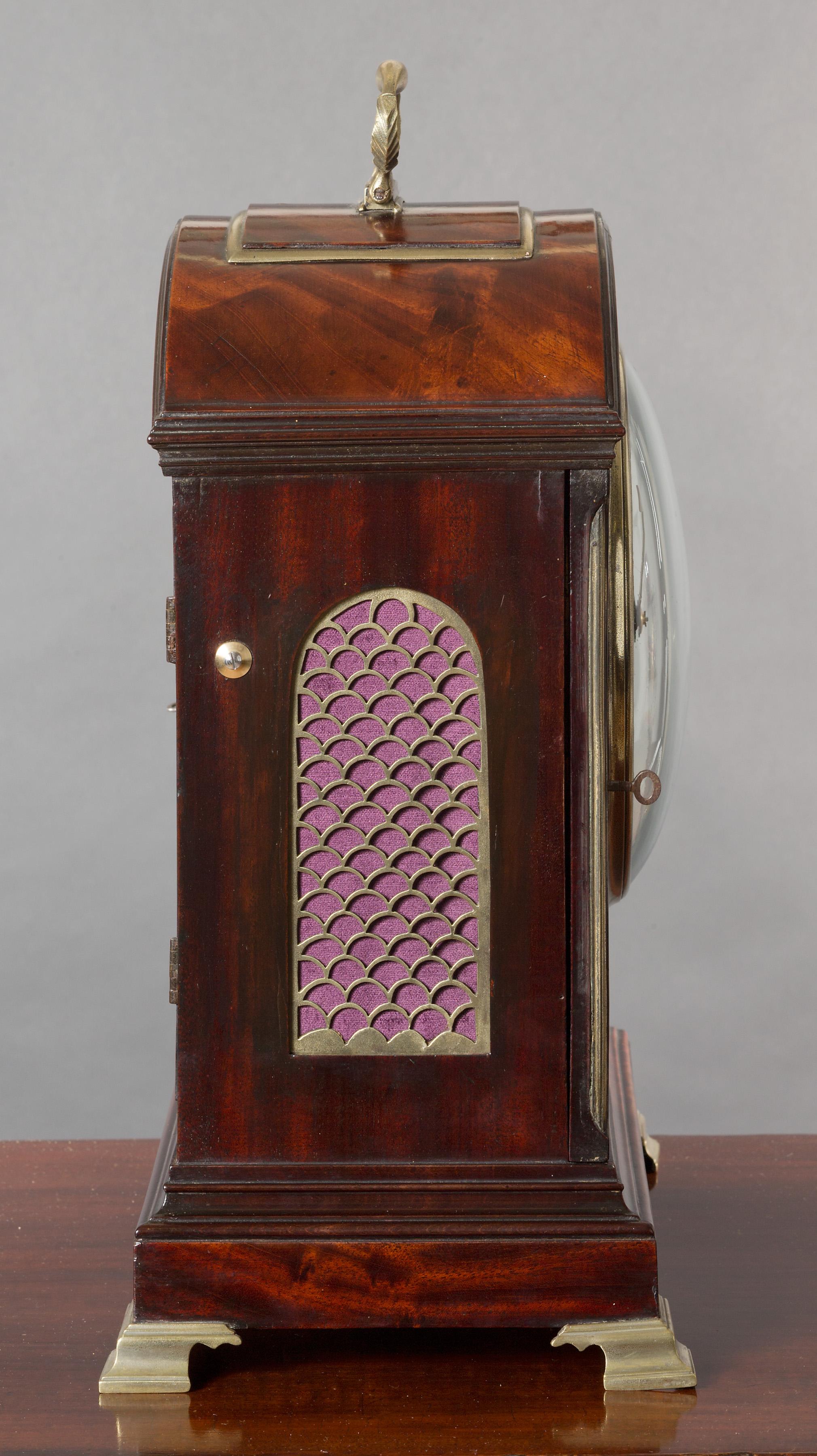 Georgian mahogany bracket clock.

Finely figured flame mahogany break arch case inset at the front and sides with fish scale silk lined sound frets standing on a raised plinth and resting on brass bracket feet. The arch with brass bound single pad