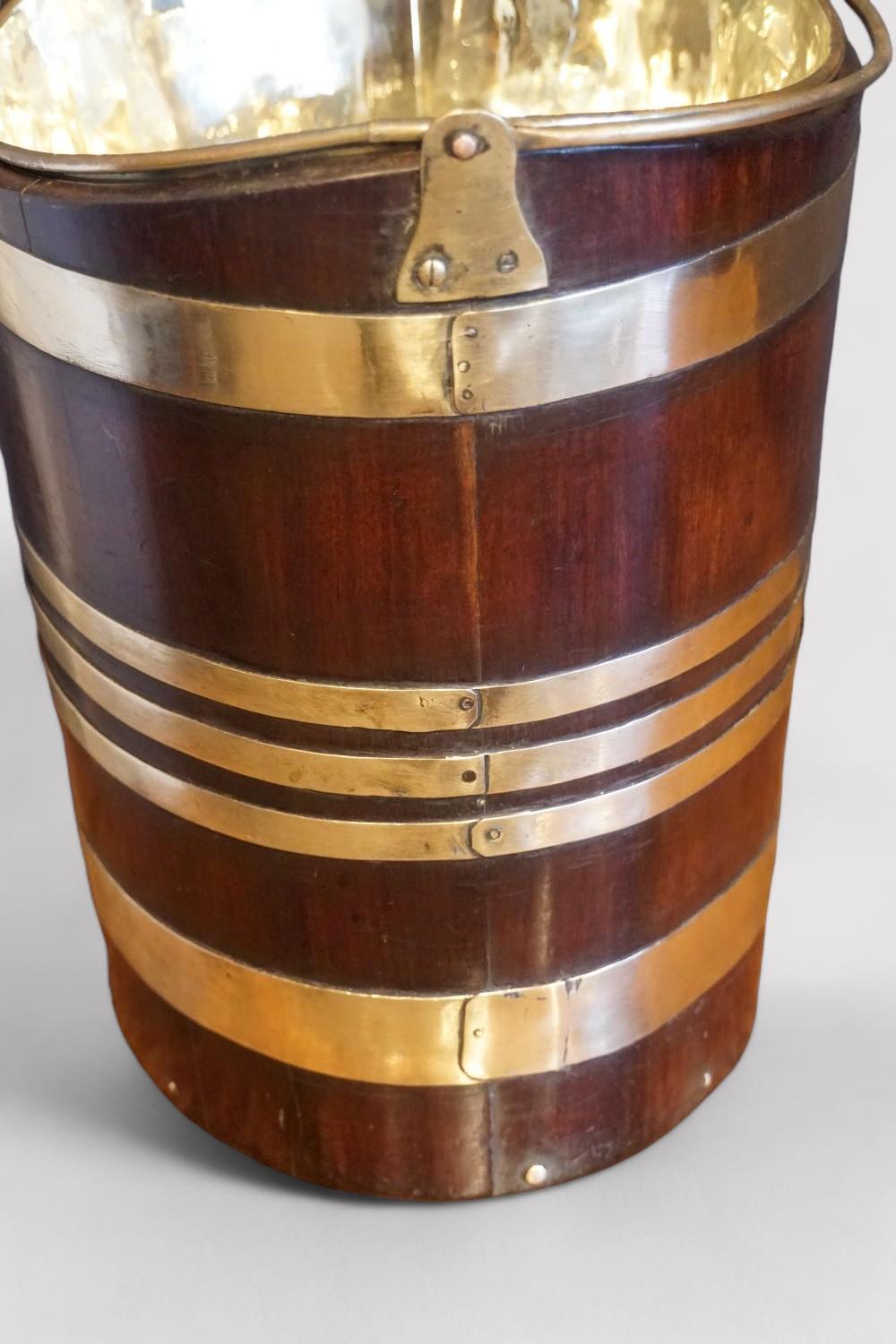 Antique brass bound mahogany bucket
This Antique brass bound mahogany bucket was made in the Georgian period.
The mahogany body made of coppered slats that are secured by the fine brass banding.
It has a lift out brass liner, this was to be used for