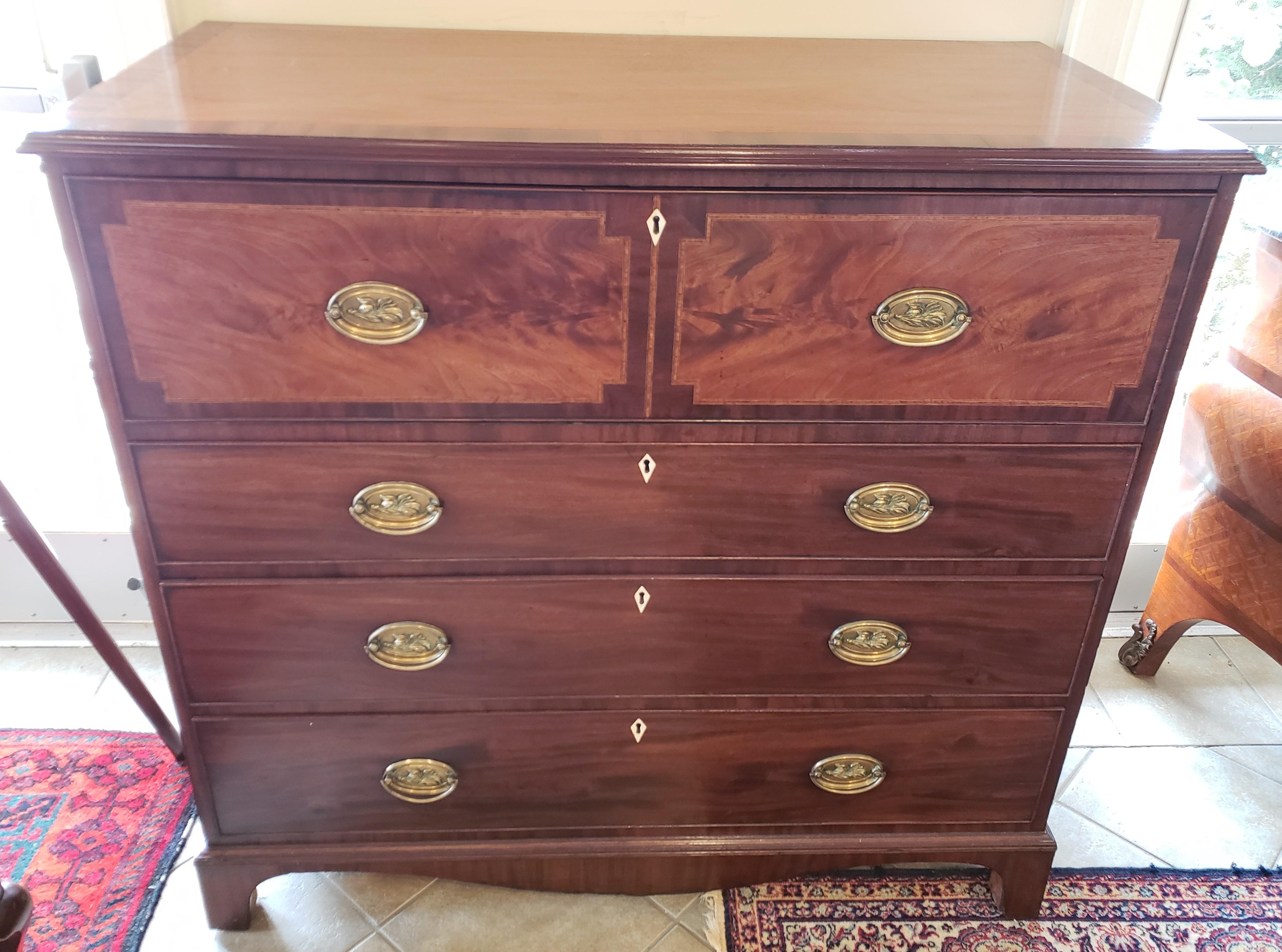 Georgian mahogany butler secretaire with crossbanding and inlay. Behind the drop front, the interior is fitted with numerous smaller drawers with Inlay. The center door features a beautiful inlayed colored urn. The drawers are made of bird's-eye