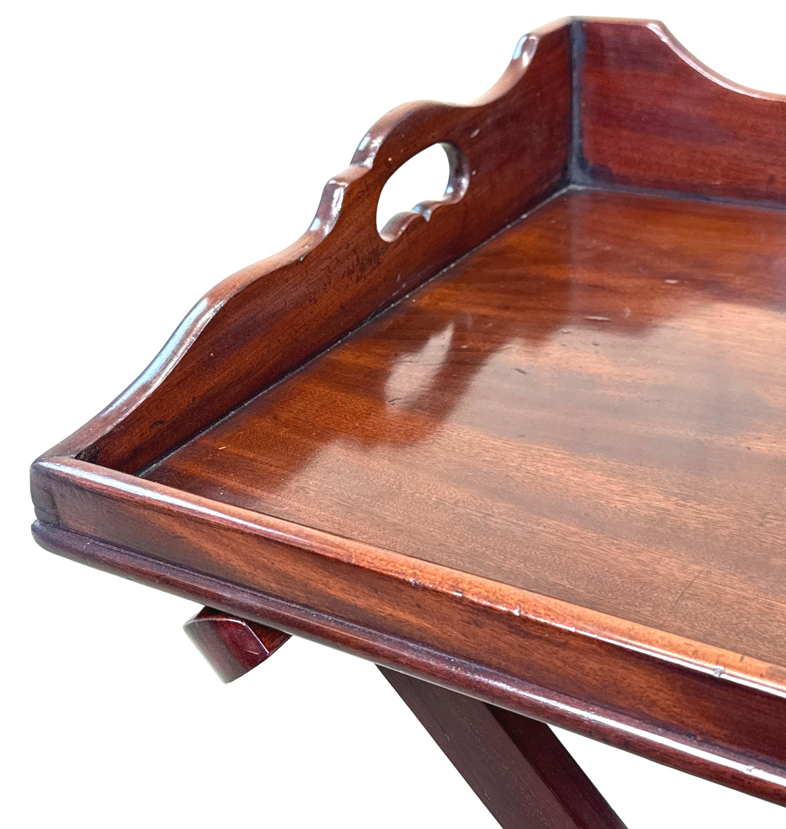 Magnífica bandeja rectangular de caoba de la época de Jorge III, finales del siglo XVIII, de color y pátina excepcionalmente ricos, con elegantes laterales perfilados, asas de transporte perforadas y parte delantera caída, elevada sobre un soporte