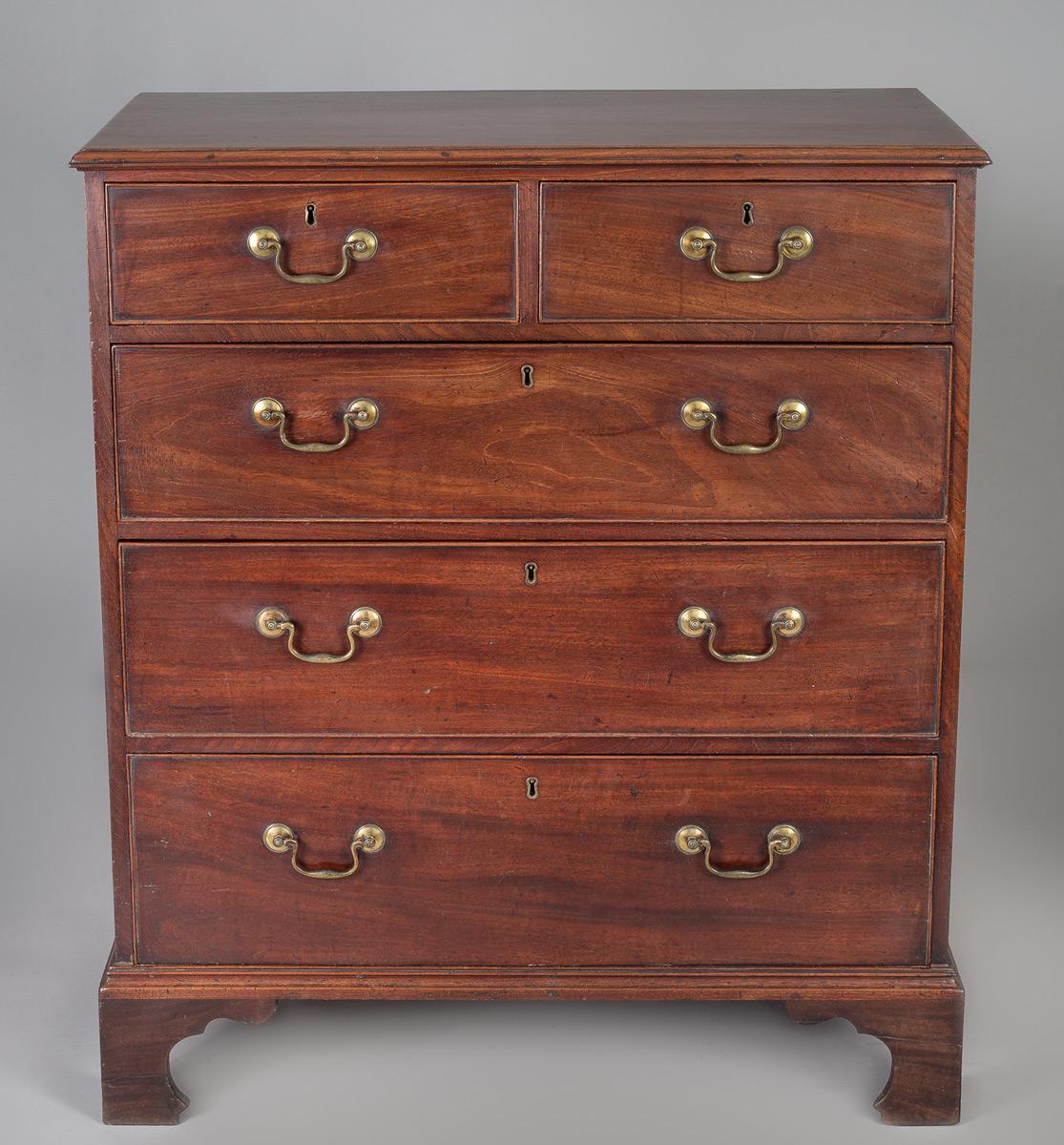 George III mahogany chest of drawers, the rectangular top with molded edge above two short and three long graduated cock-beaded drawers, original brass swan-neck handles and escutcheons, raised on tall shaped bracket feet. It has a lovely patina and