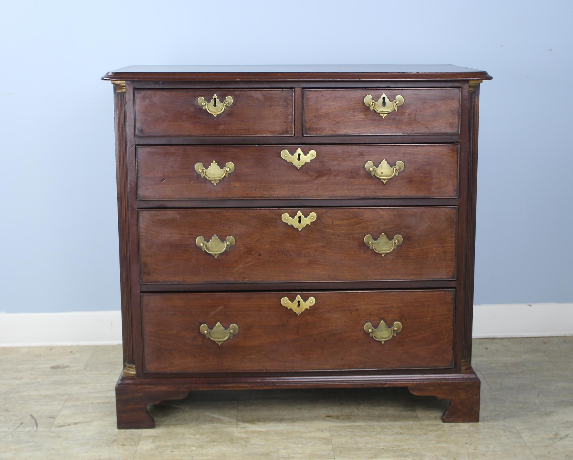 A handsome smaller early chest of drawers, with several key period details. The reeded quarter columns accented with brass capitals at top and bottom, the beading around the edge of the drawers and the ogee feet. Classic two-over-three construction.