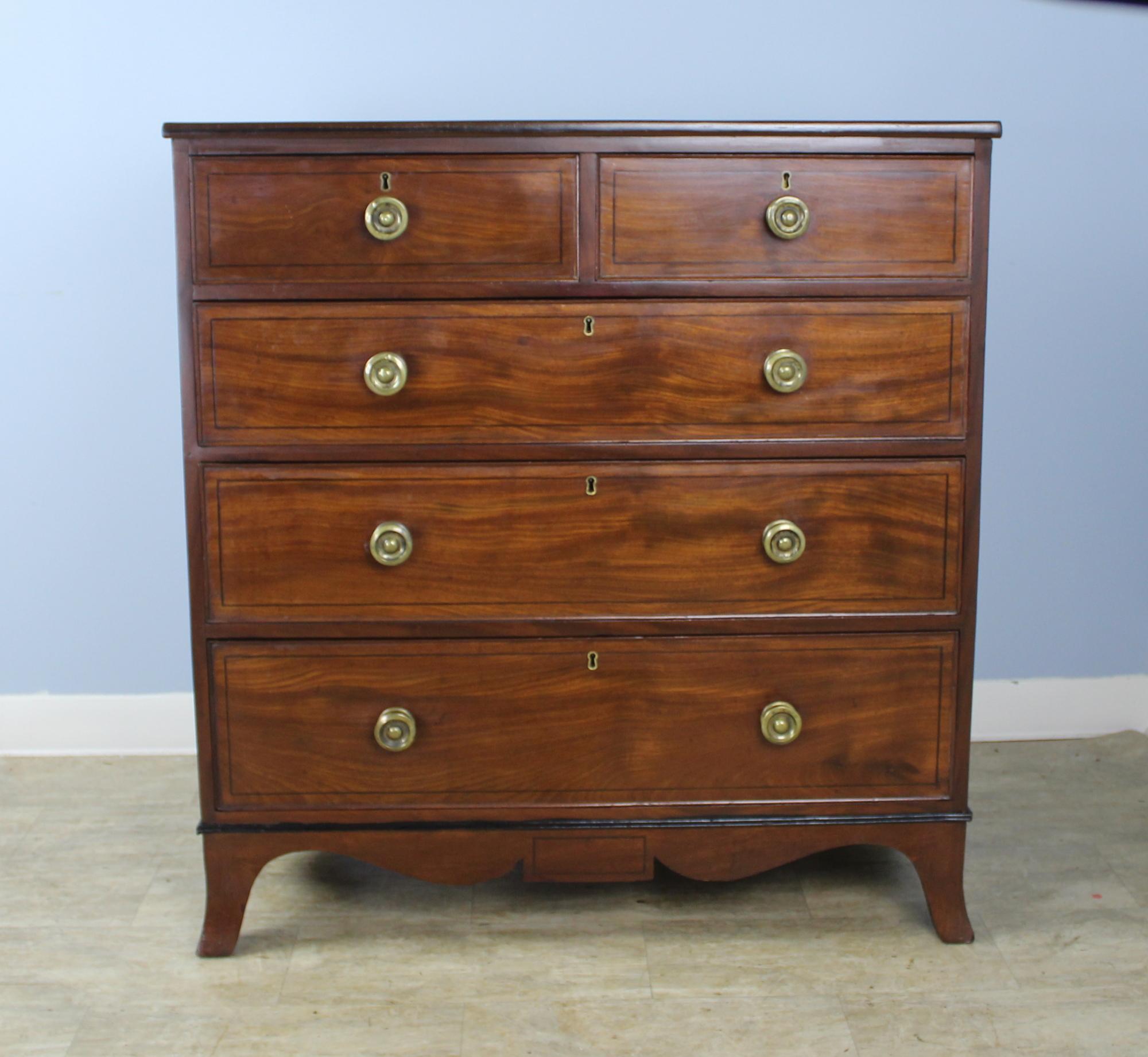An elegant mahogany bureau in very good antique condition. The mahogany is a rich medium color with a lovely grain. Details of note include the decorative ebony stringing, discreet mouldings on the drawers, and beautifully wrought brass drawer