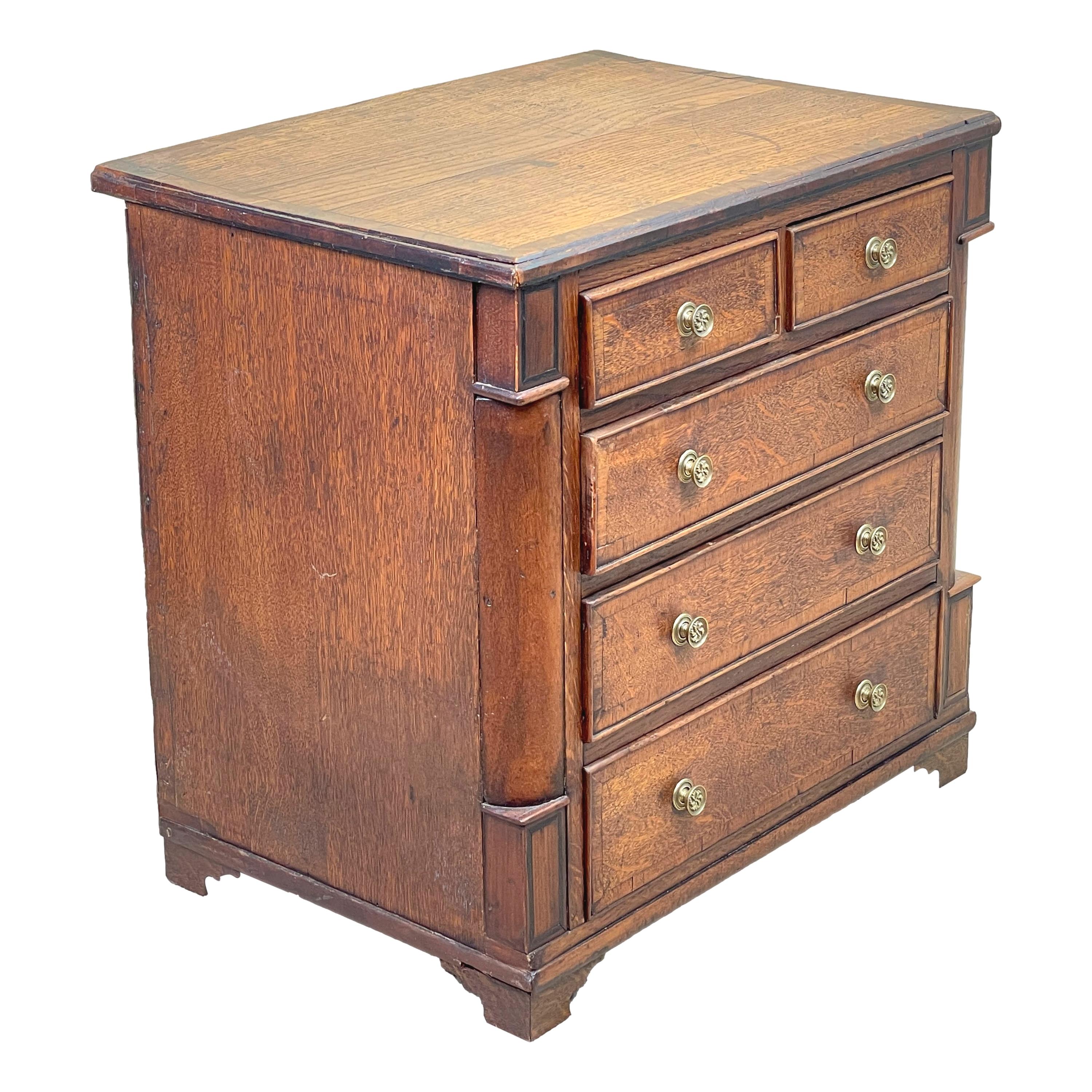 A very attractive George III period oak childs chest having well
Figured and crossbanded top above two short and three long
Drawers flanked by curved corners raised on replaced bracket
Feet

(This charming little childs chest is the perfect