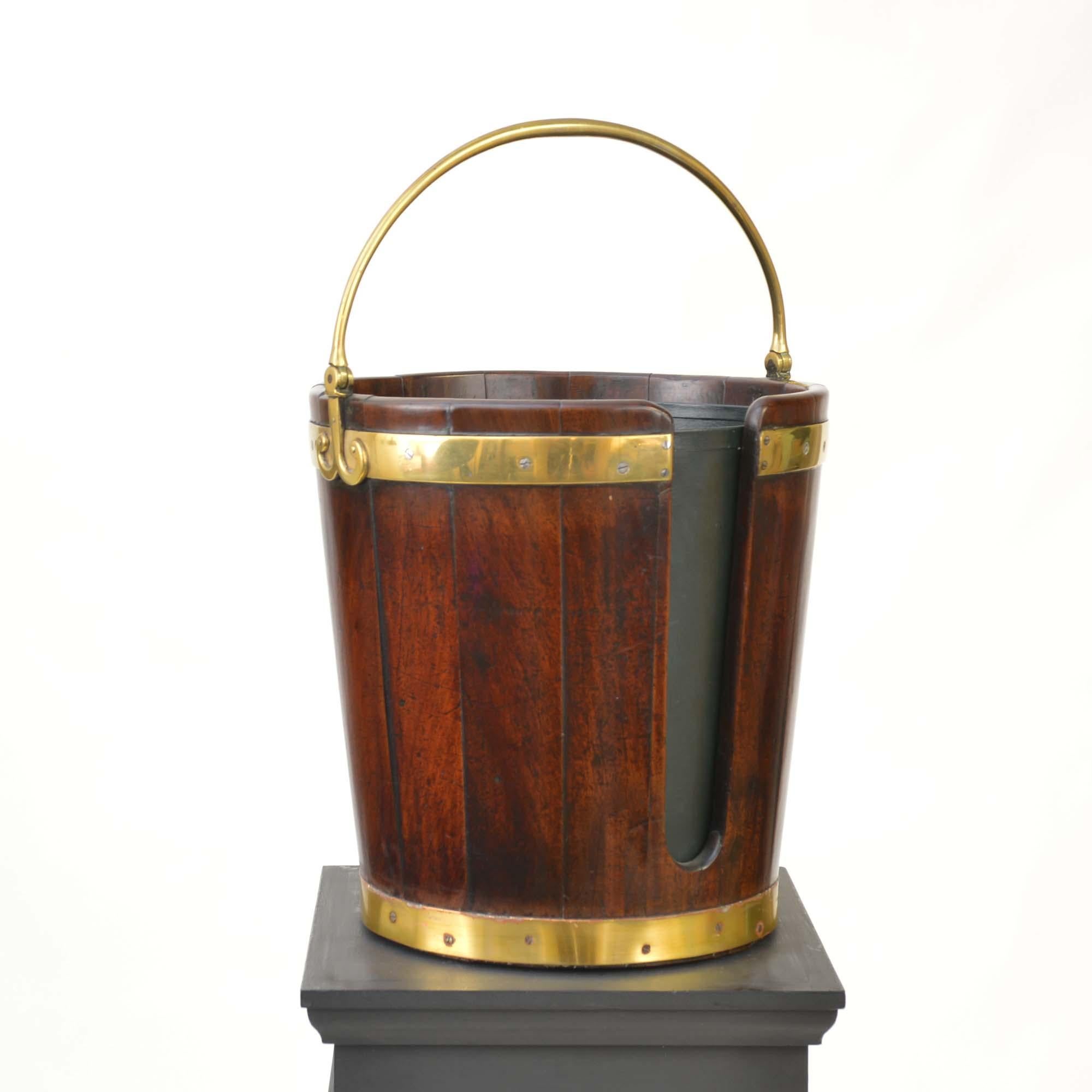 Secchio georgiano in mogano con piatto cooperato, rilegato in ottone, con manico pieghevole in ottone fuso per il trasporto, ora con rivestimento in tole (metallo) di data successiva.
Inglese, circa 1780 - 1800.

I lunghi passaggi che spesso