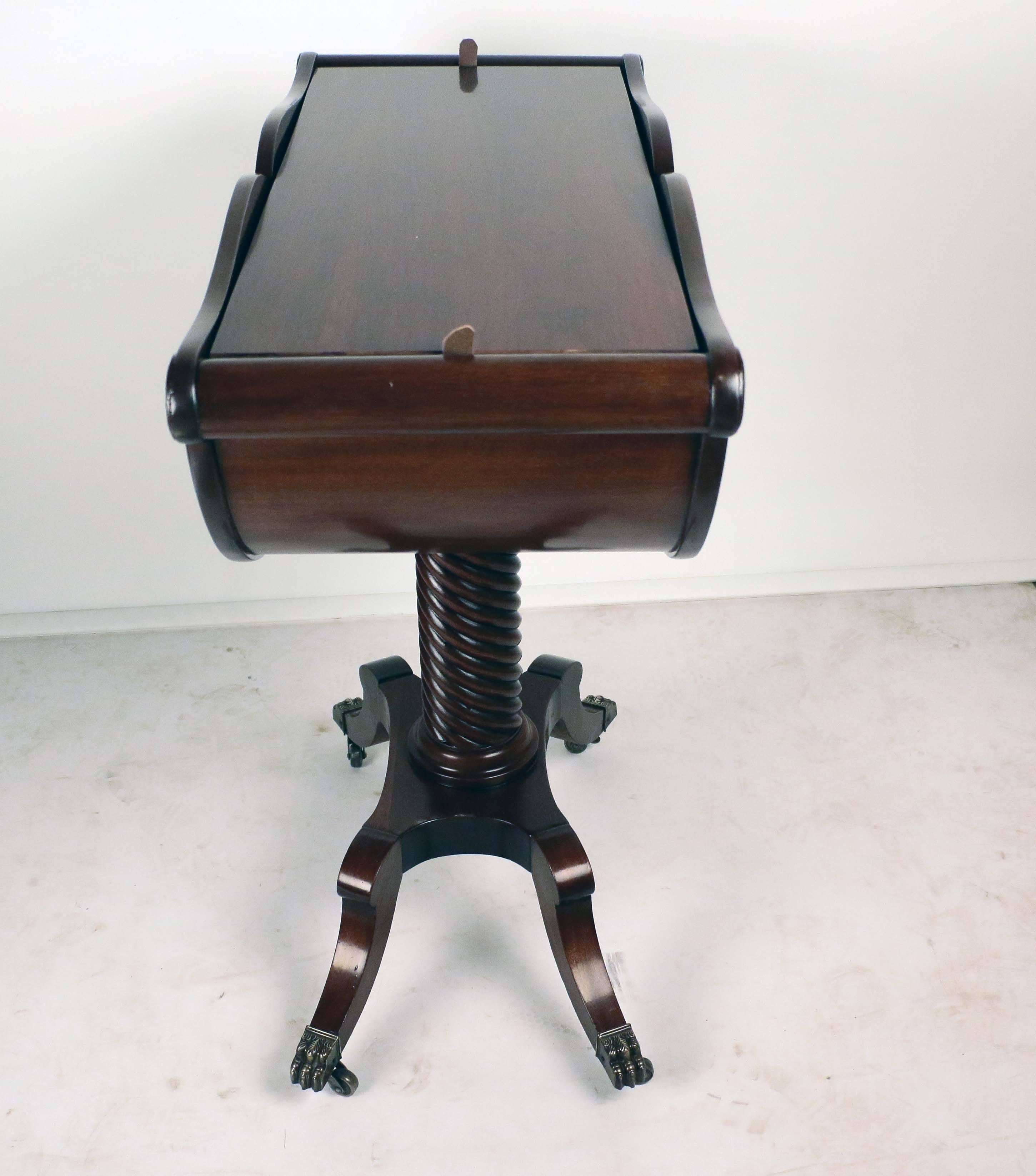 A unusual shaped Georgian mahogany work table with lift top, a serpentine upper edge with demilune shaped body supported by a barley twist centre column on a quatrafoil base and legs ending in a brass lion foot casters.
This table is shaped like a