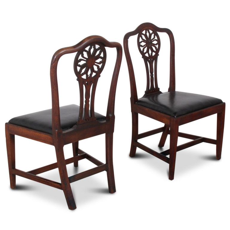 A set of four English Georgian mahogany dining chairs, the backs with an elegantly shaped and pierce-carved back splat featuring a ‘wheel’ motif, the drop-in seat above simple square-tapering legs. Circa 1820.



      
