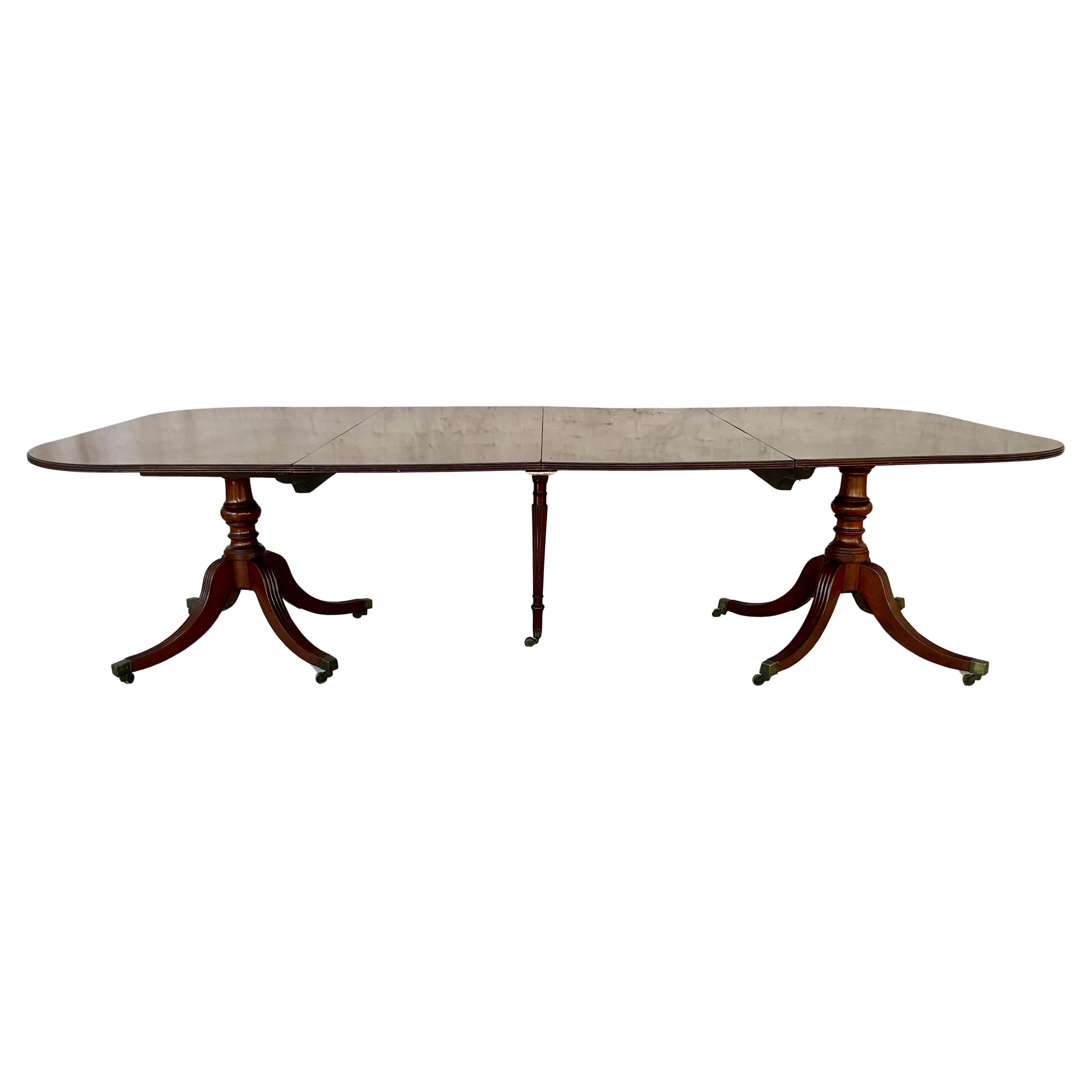 Table de salle à manger en acajou George IV du début du 19ème siècle avec deux feuilles. La table repose sur deux élégants socles jumeaux, chacun doté de colonnes balustres tournées sur des pieds cannelés à l'extérieur se terminant par des capuchons