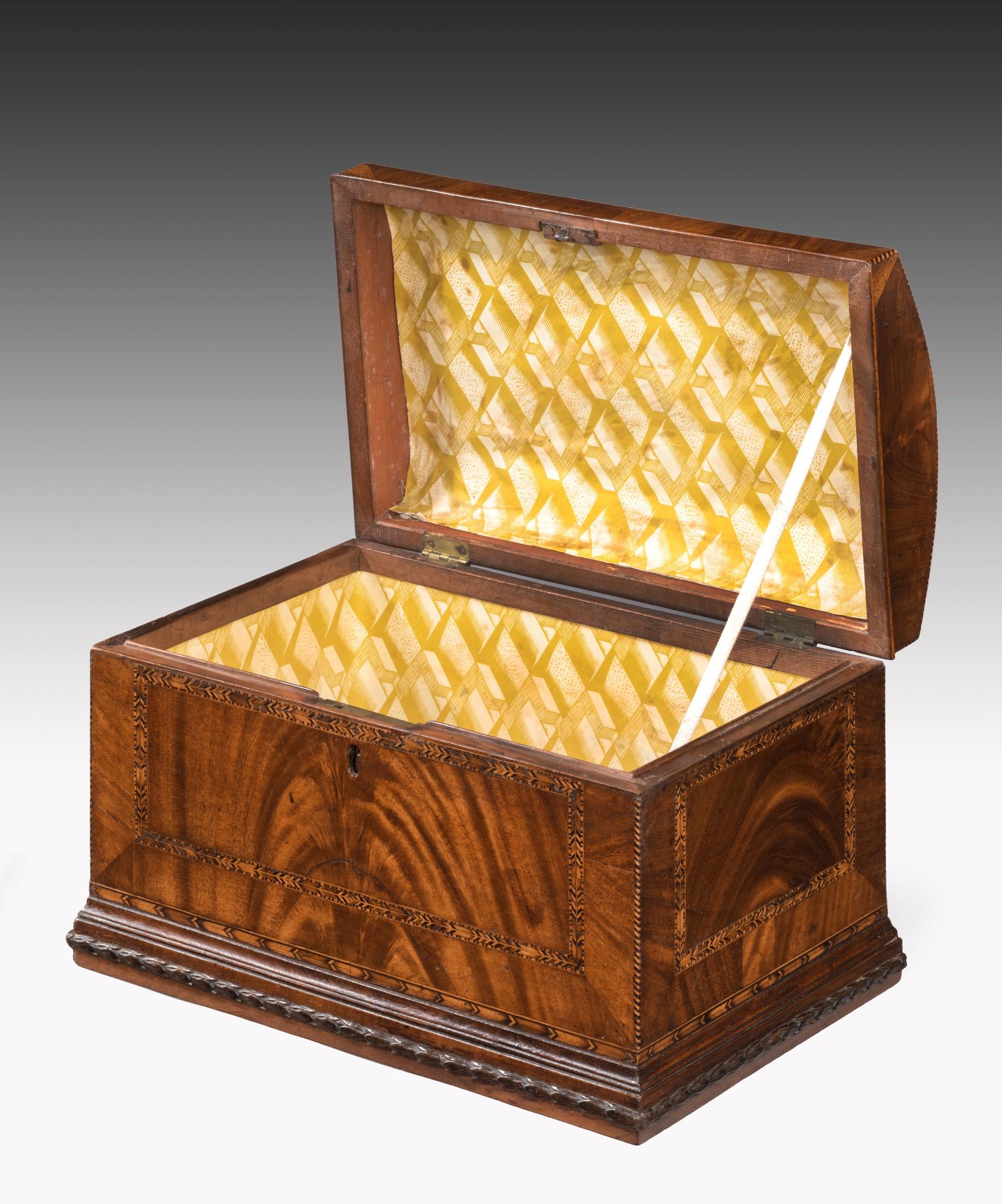 A superb Georgian mahogany domed box; the domed lid veneered in well figured mahogany and inlaid with feather banding and barber's pole stringing and retaining its original fire gilded handle; the sides veneered in flame mahogany and crossbanded in
