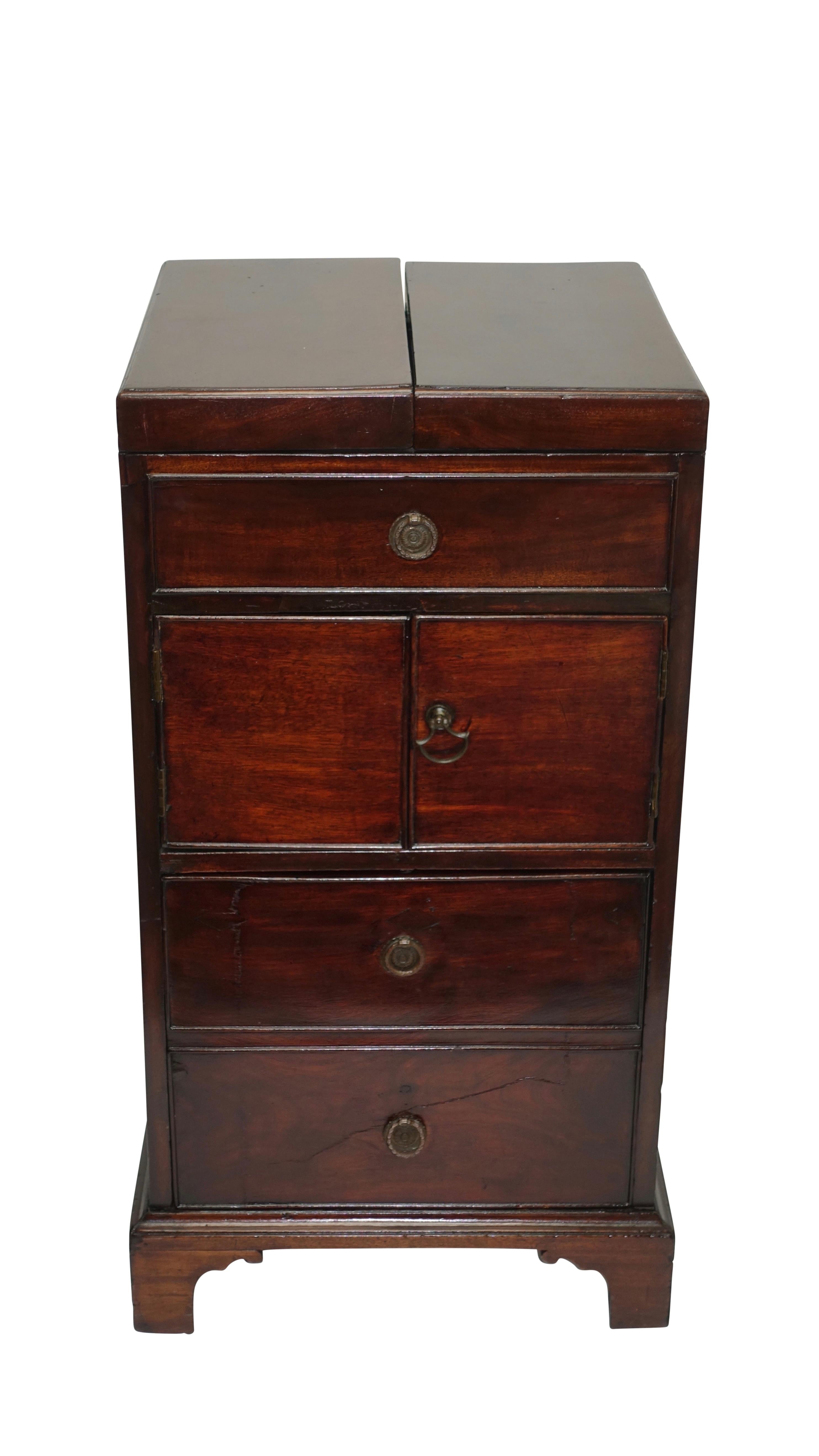 Georgian mahogany washstand with flip open top, the inside fitted with lift up above a false drawer, a pair of doors open to reveal cabinet space above a deep drawer, standing on bracket feet with brass handles on either side. Showing signs of early