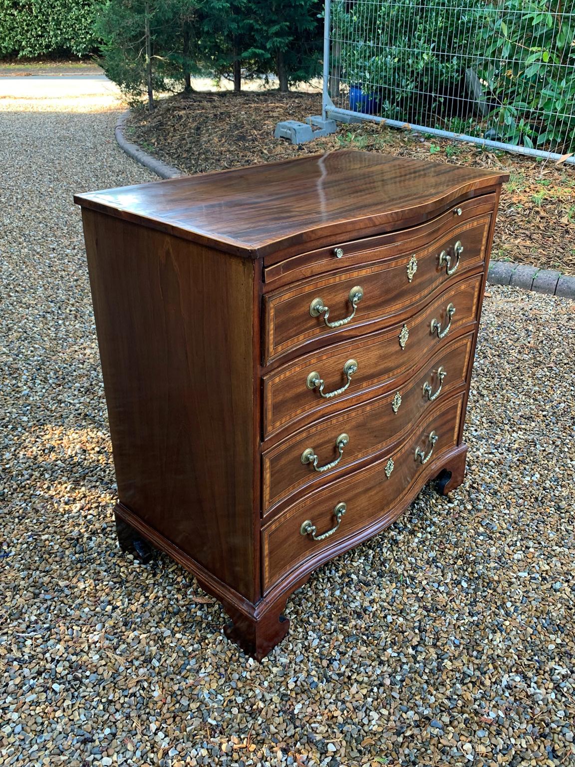 Georgian Mahogany Serpentine Chest Of Drawers, heavily inlaid with a brushing slide. Four long oak lined drawers and brass fittings throughout.

circa 1820.

Dimensions:
Height: 33 inches - 85 cms
Width: 31 inches - 79 cms
Depth: 18 inches -