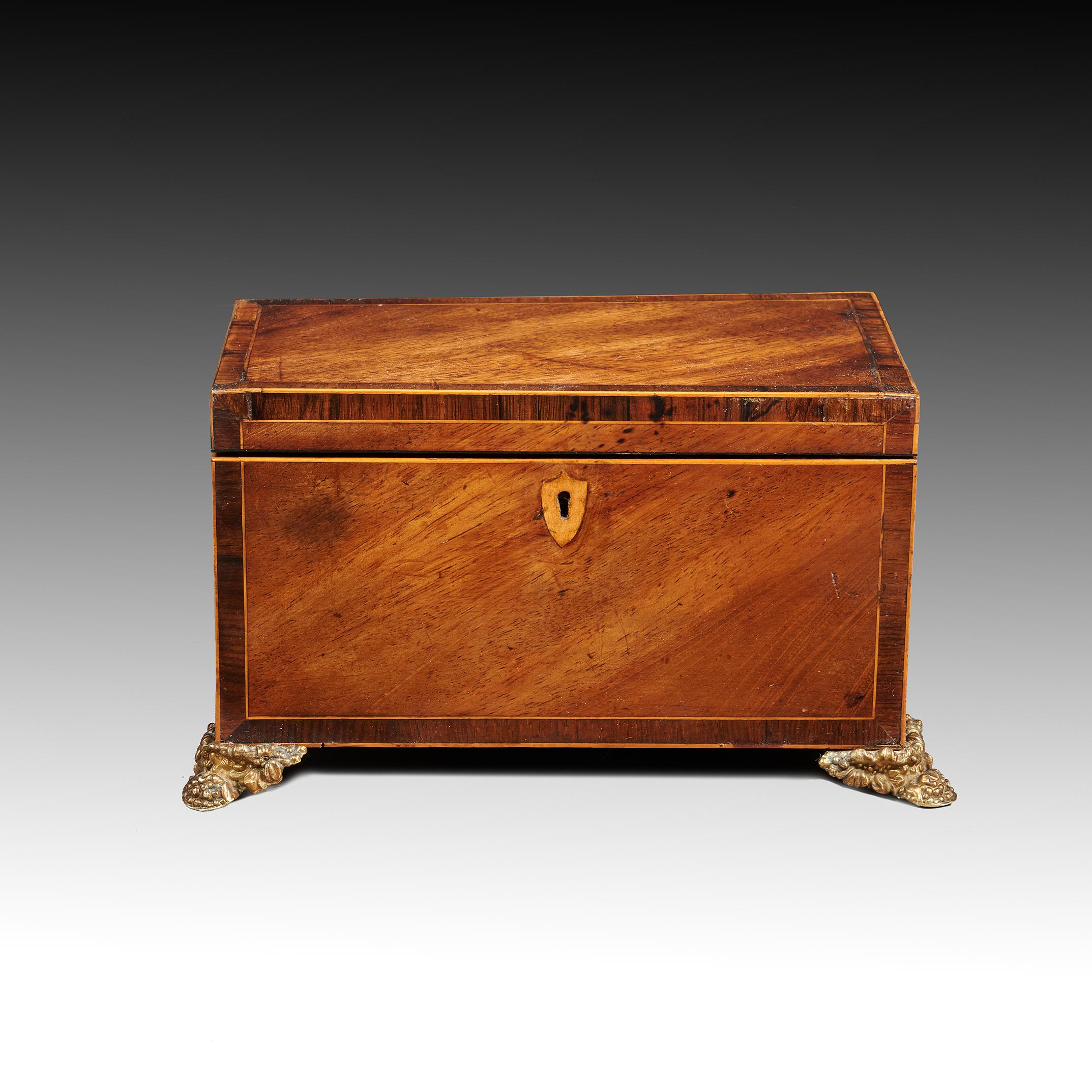 A neat George III mahogany and boxwood inlaid tea caddy raised on original brass feet

English circa 1800.


The rectangular lift up top opening to reveal a fitted interior of two lidded compartments.
The top has a slight bow which has been