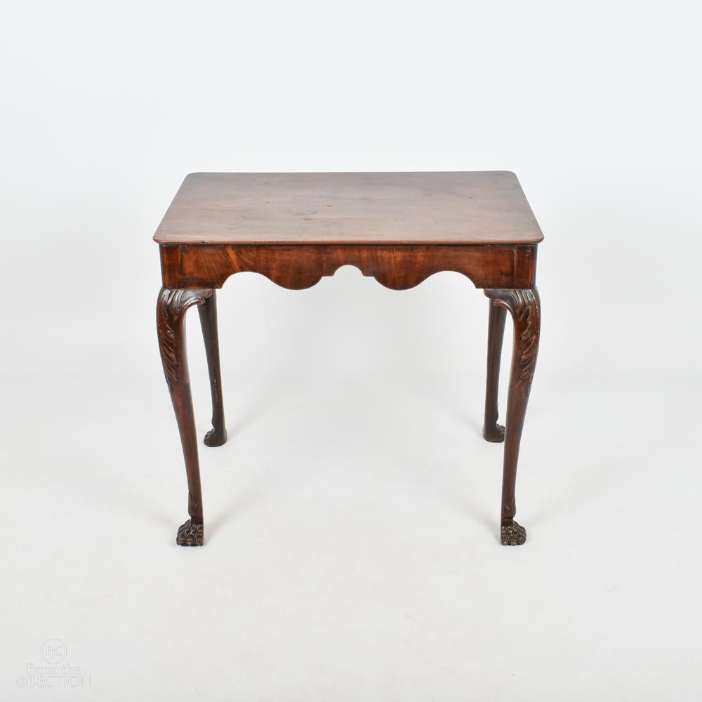 A Mahogany Georgian Irish Silver table with carving beneath the top circa 1770. The rectangular top above scalloped frieze supported on cabriole leg terminating on carved claw foot with foliage detail at the top of each leg. With lovely age to it